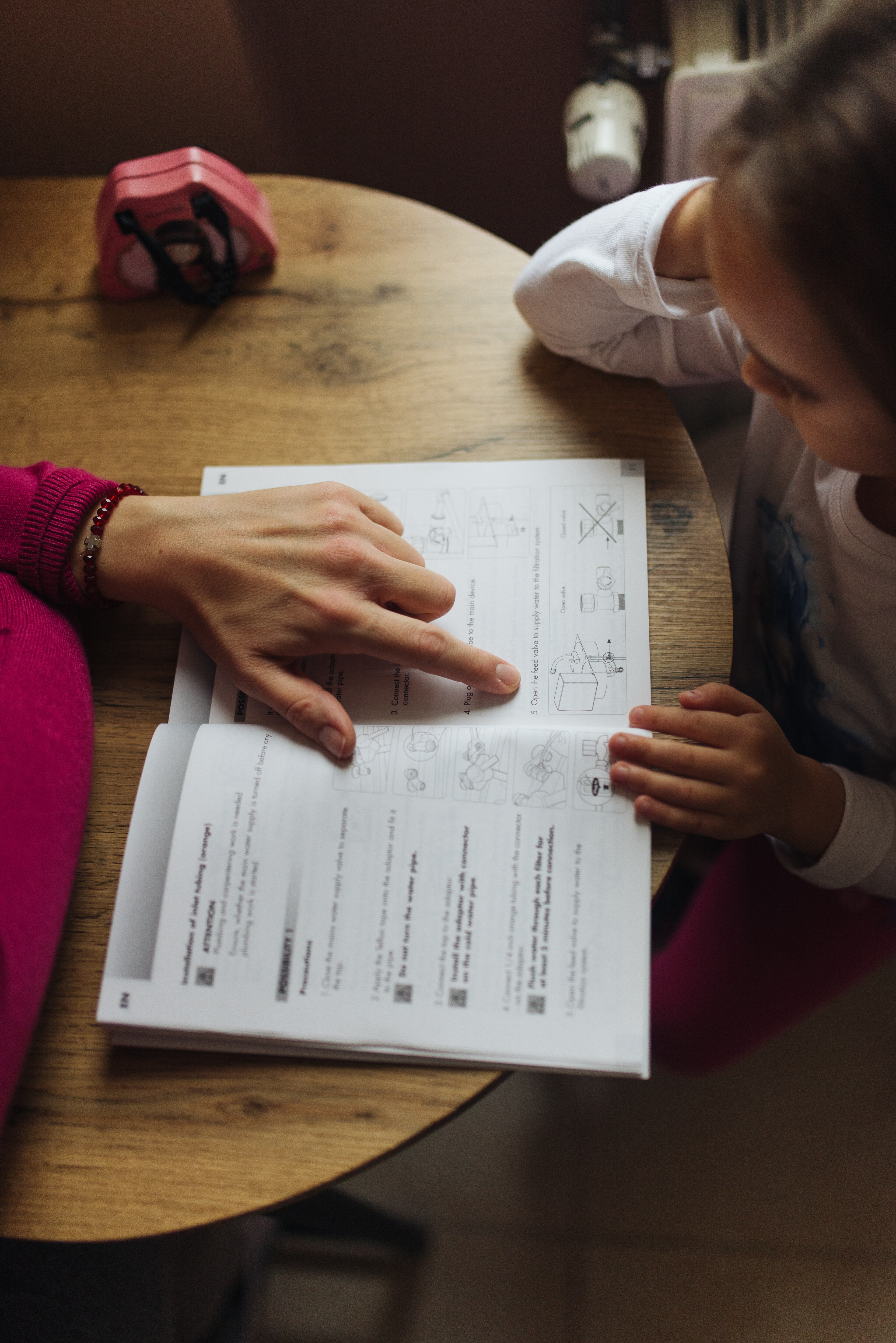 A parent helps a young child with homework at home