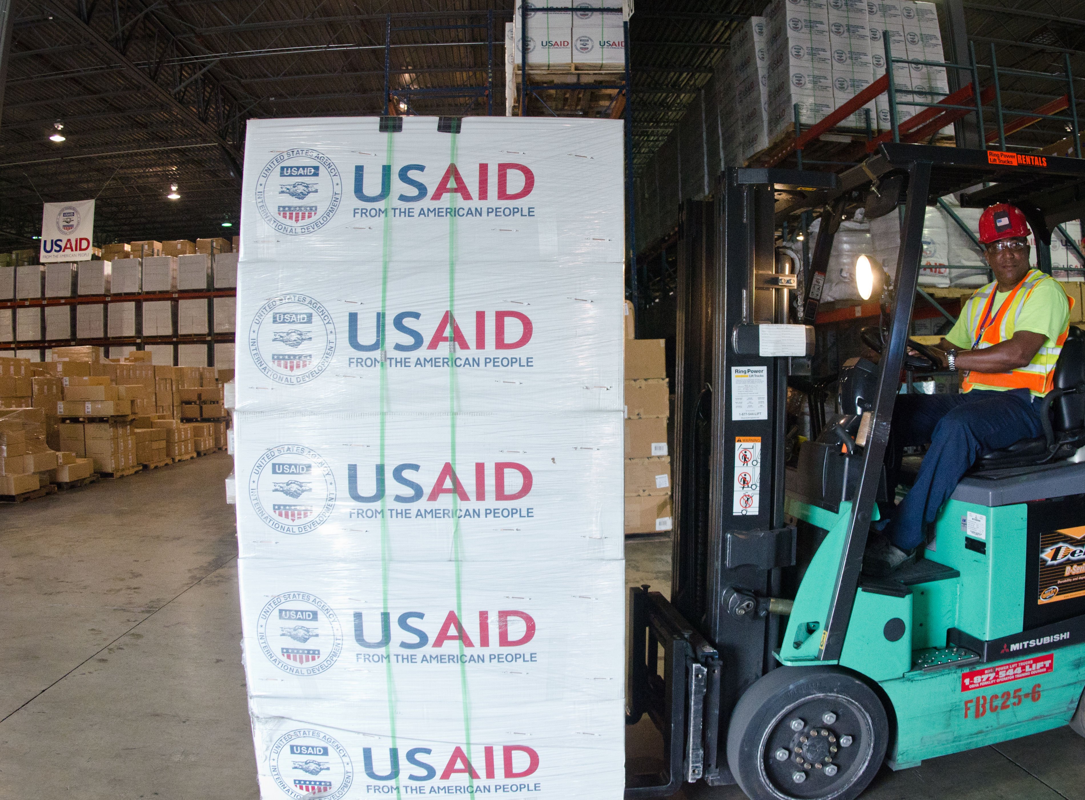 Warehouse workers moving goods on forklifts inside a large storage facility
