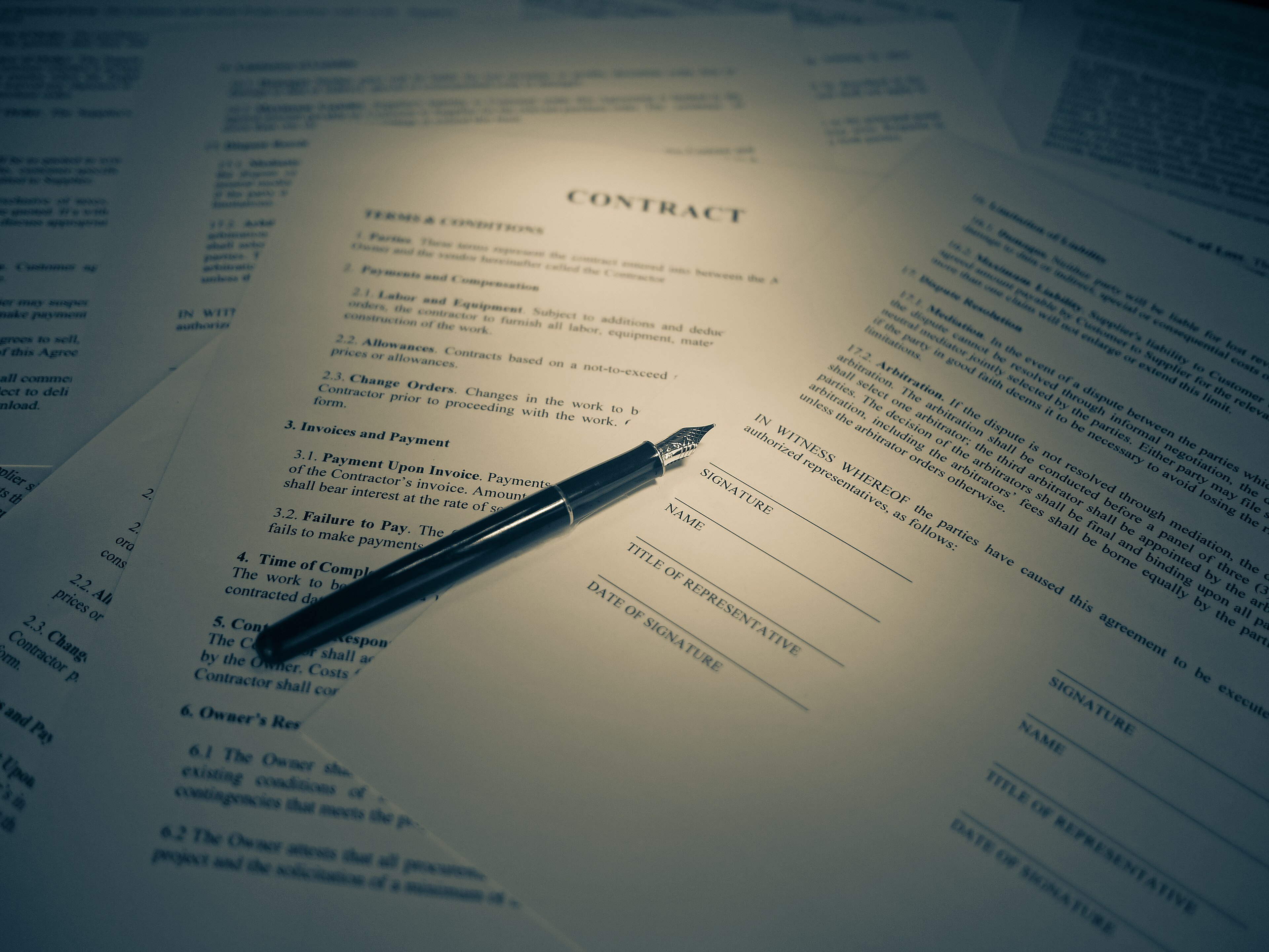 A legal document being signed, with a pen resting on the signature line