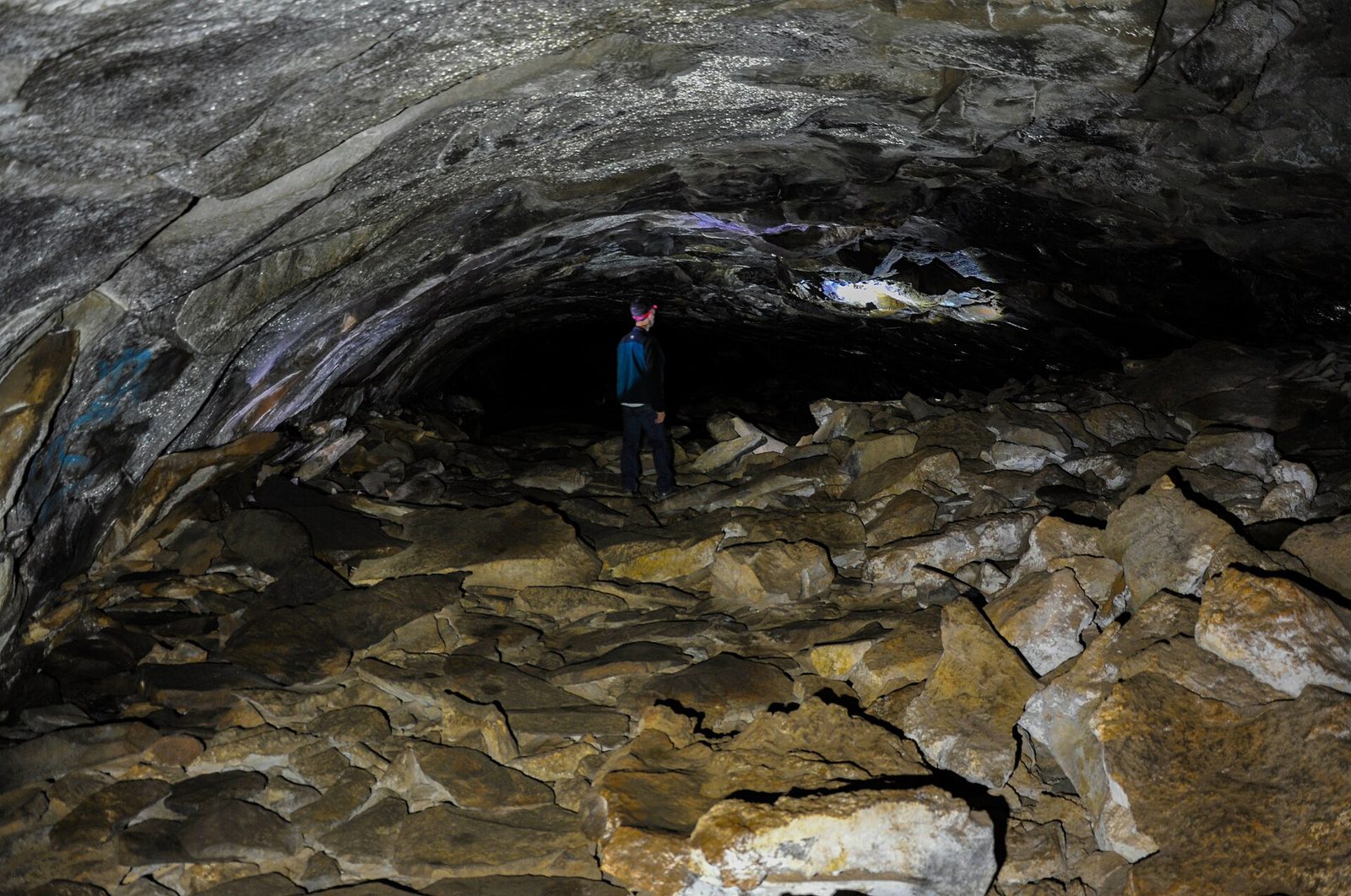 A lone person standing inside a huge, dark cave