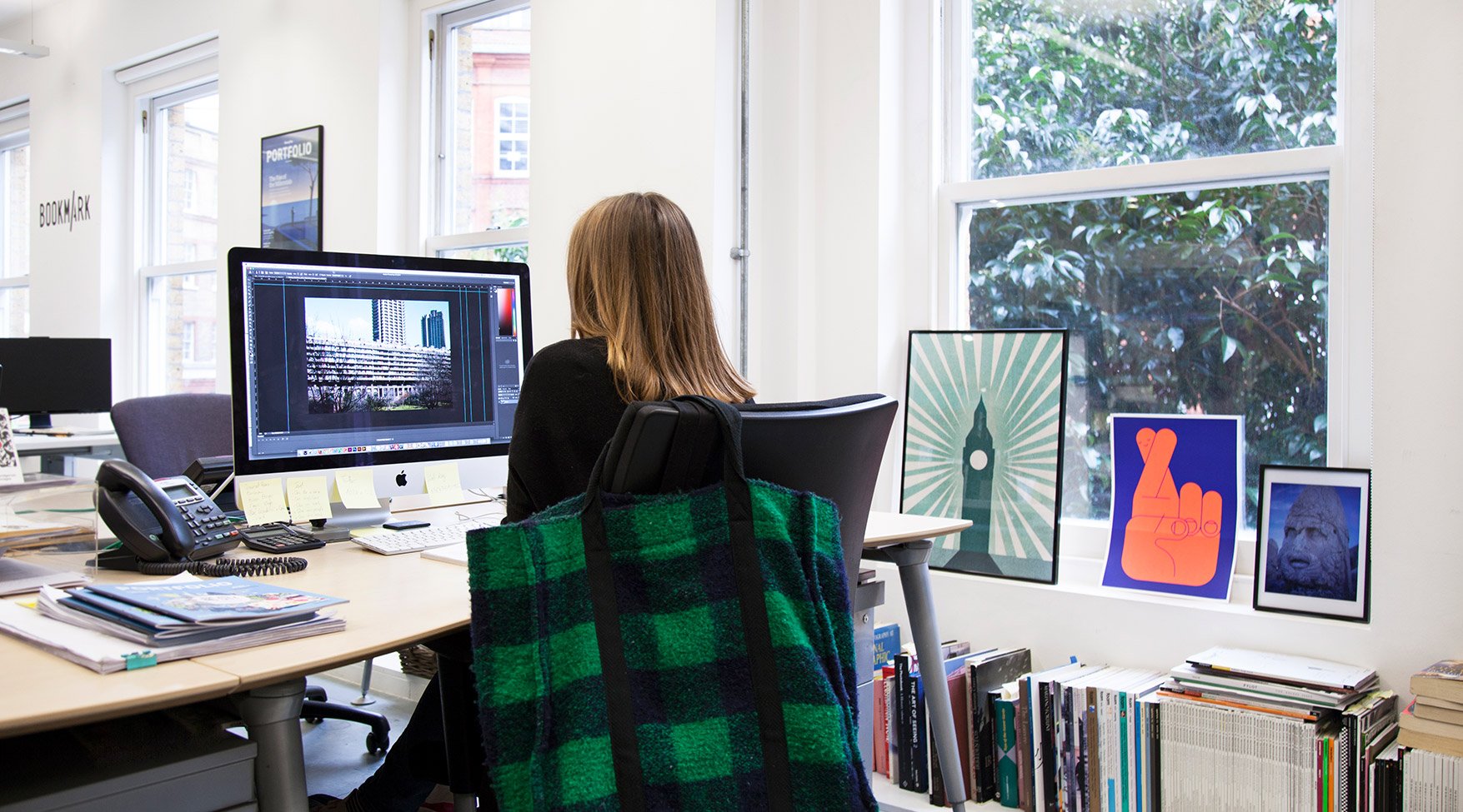 A woman works at a desk on a computer in an office