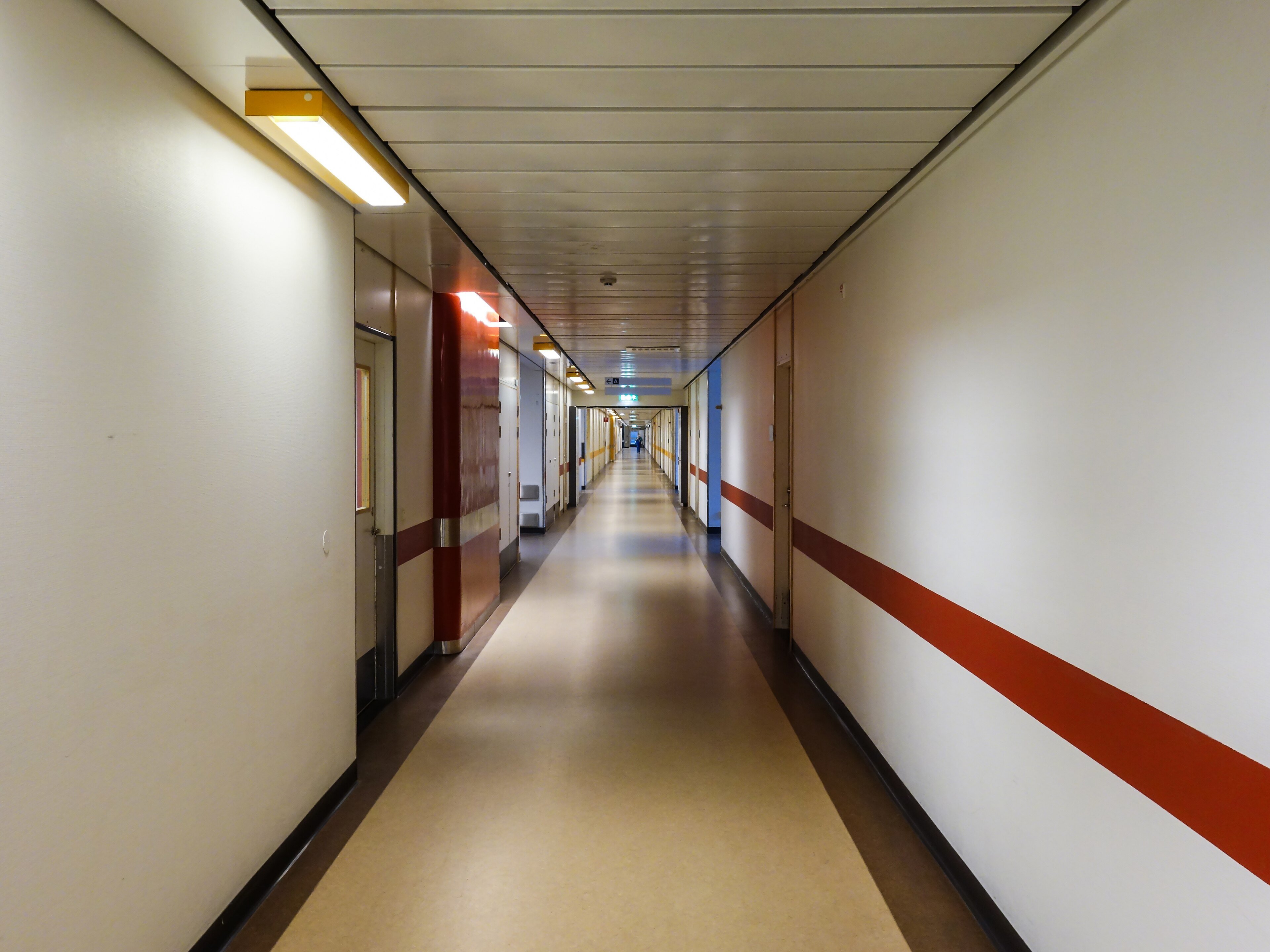 An empty, brightly lit hospital corridor with closed doors on both sides