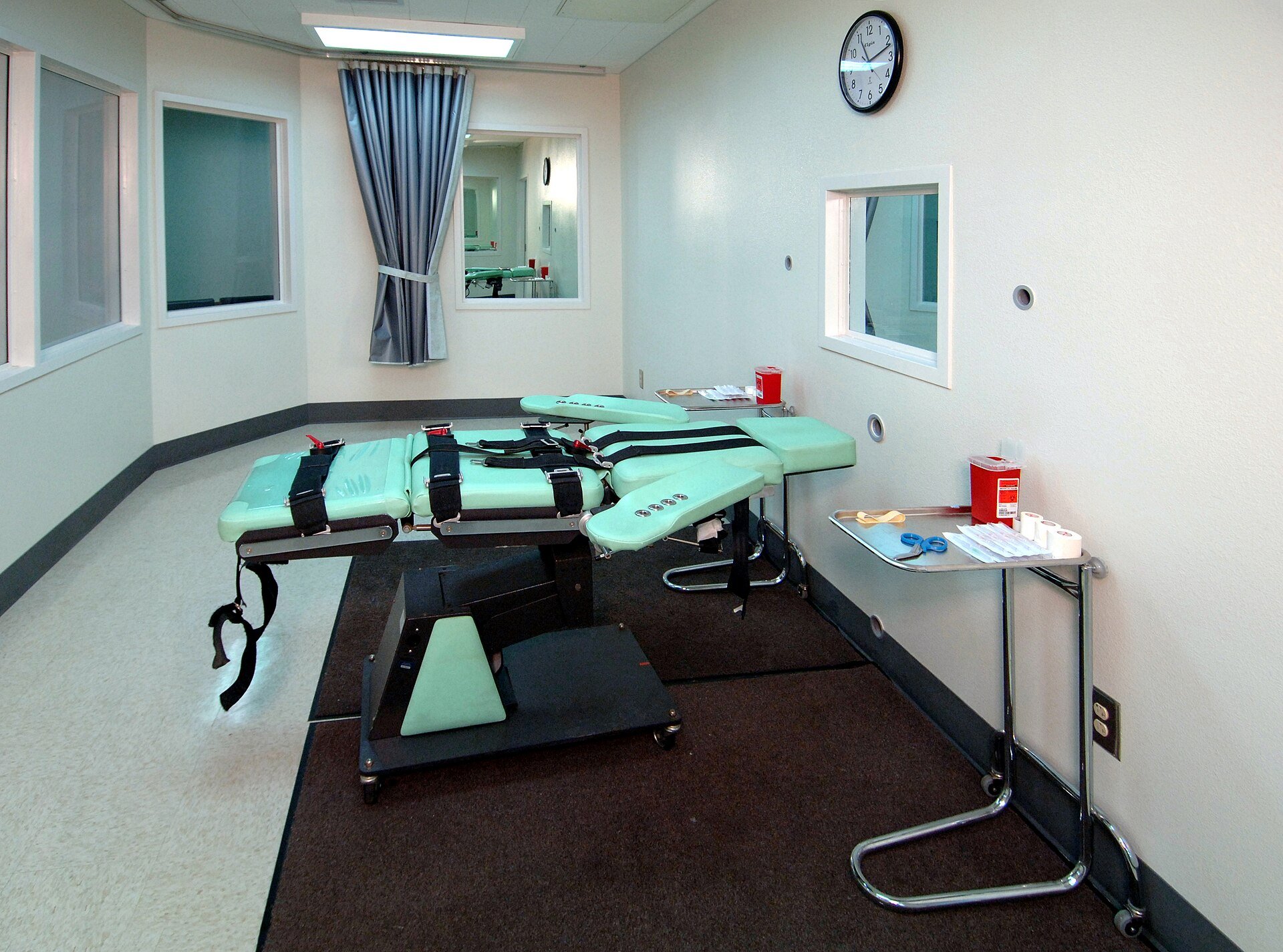 Empty lethal injection room with a gurney, a drug tray and viewing windows