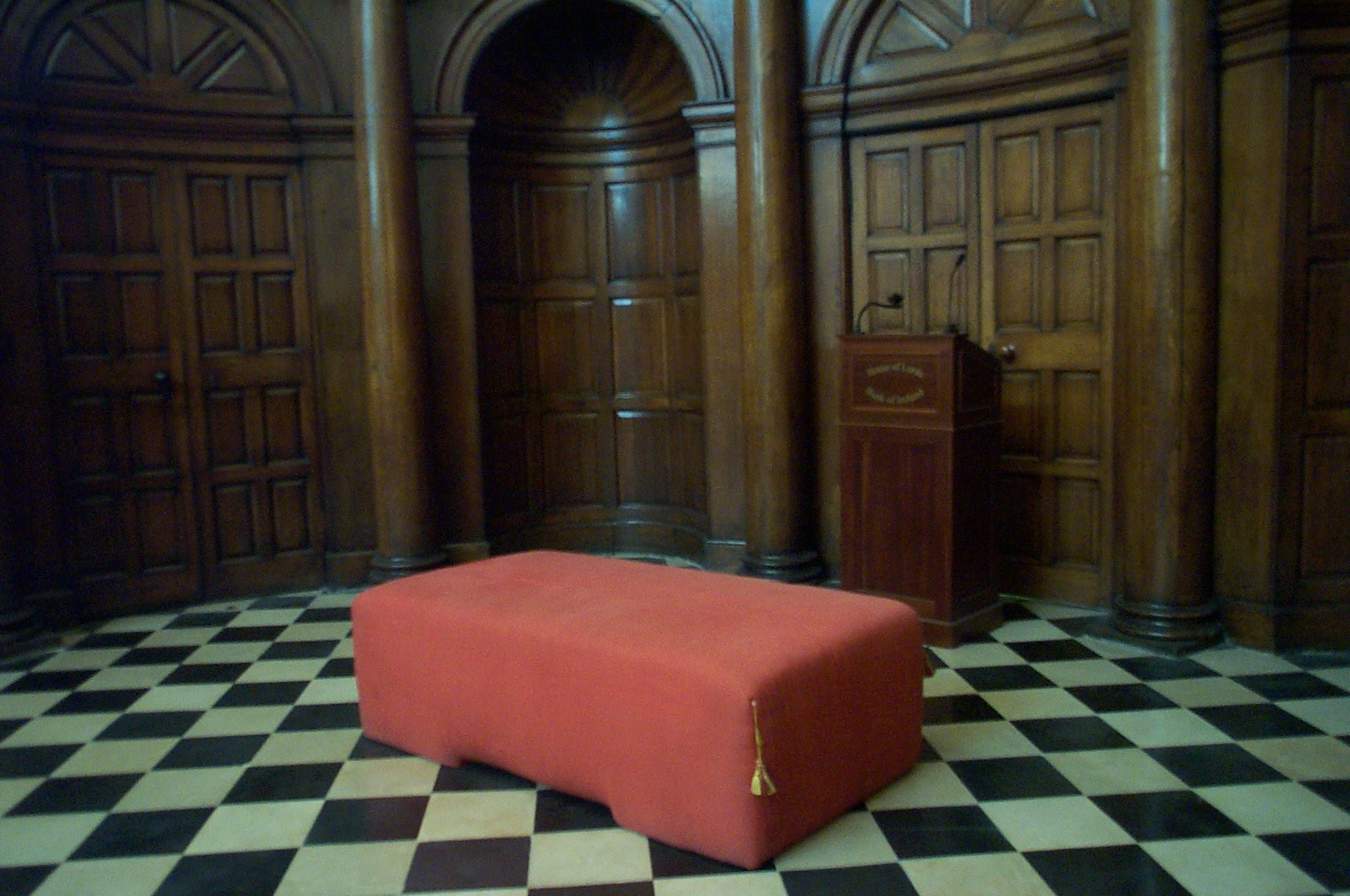 A red woolsack seat in an old parliament chamber