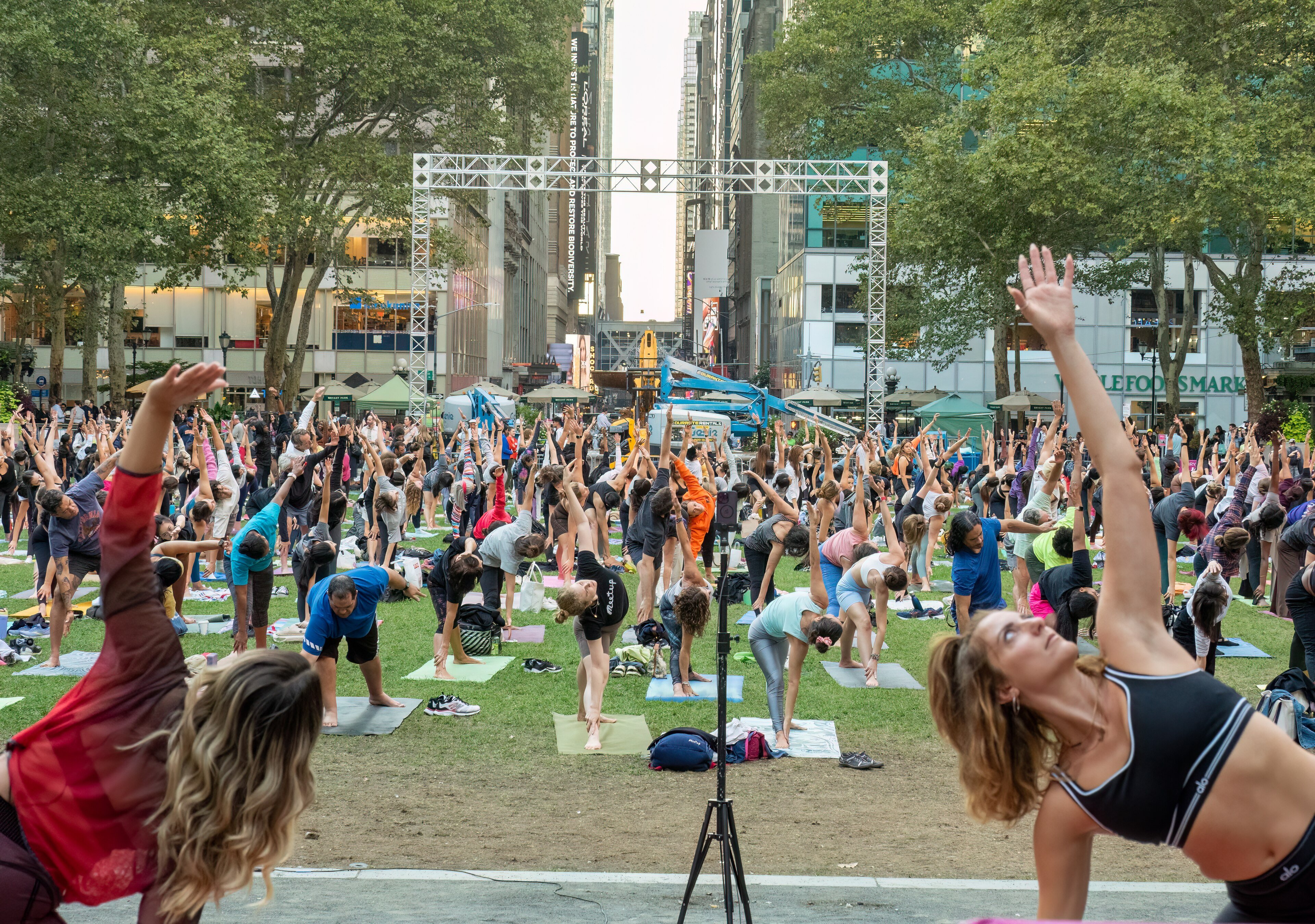 Rows of people doing yoga on mats on the lawn of Bryant Park in New York