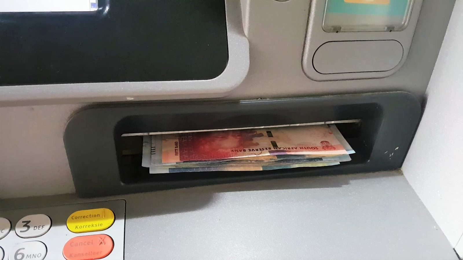 Rand banknotes sticking out of an ATM cash slot
