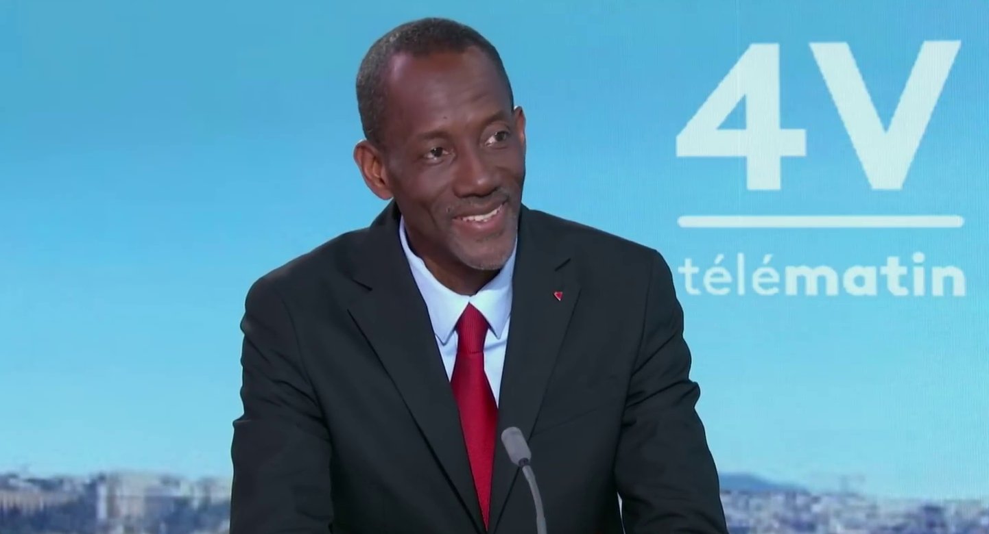 Bally Bagayoko, mayor of Saint-Denis, smiling in a dark suit and red tie in a French television studio