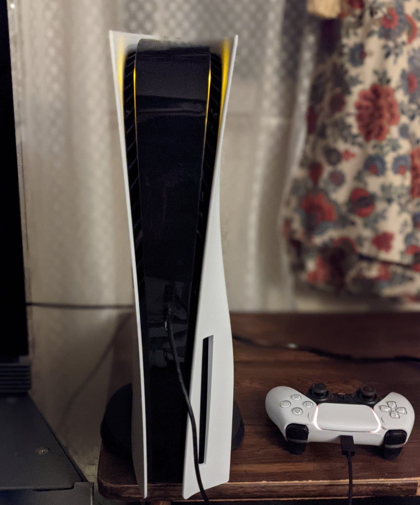 A PlayStation 5 console standing upright next to a white DualSense controller
