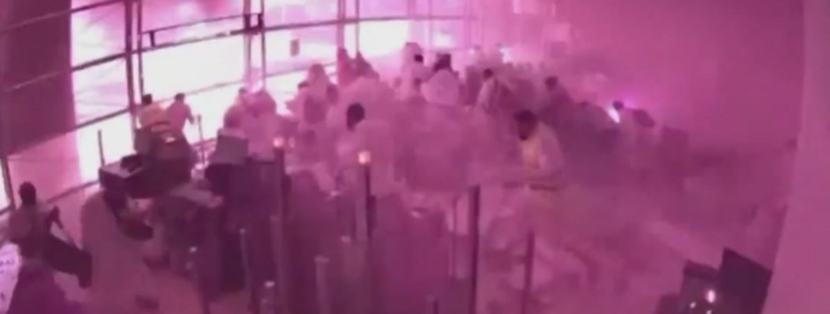 CCTV still of a Riyadh airport hall filling with pink smoke as people in white robes run