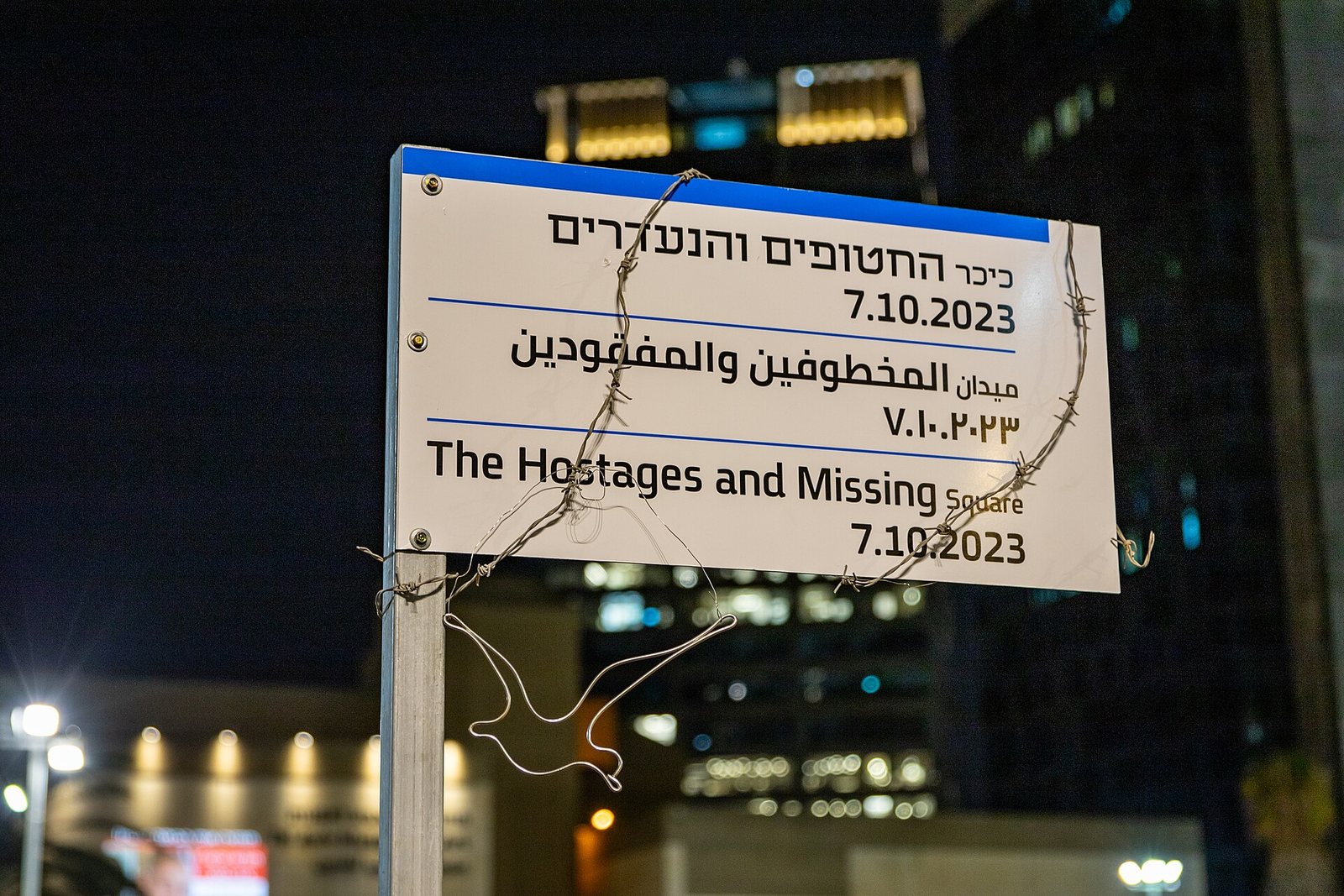 Street sign for the Hostages and Missing Square in Tel Aviv wrapped in barbed wire