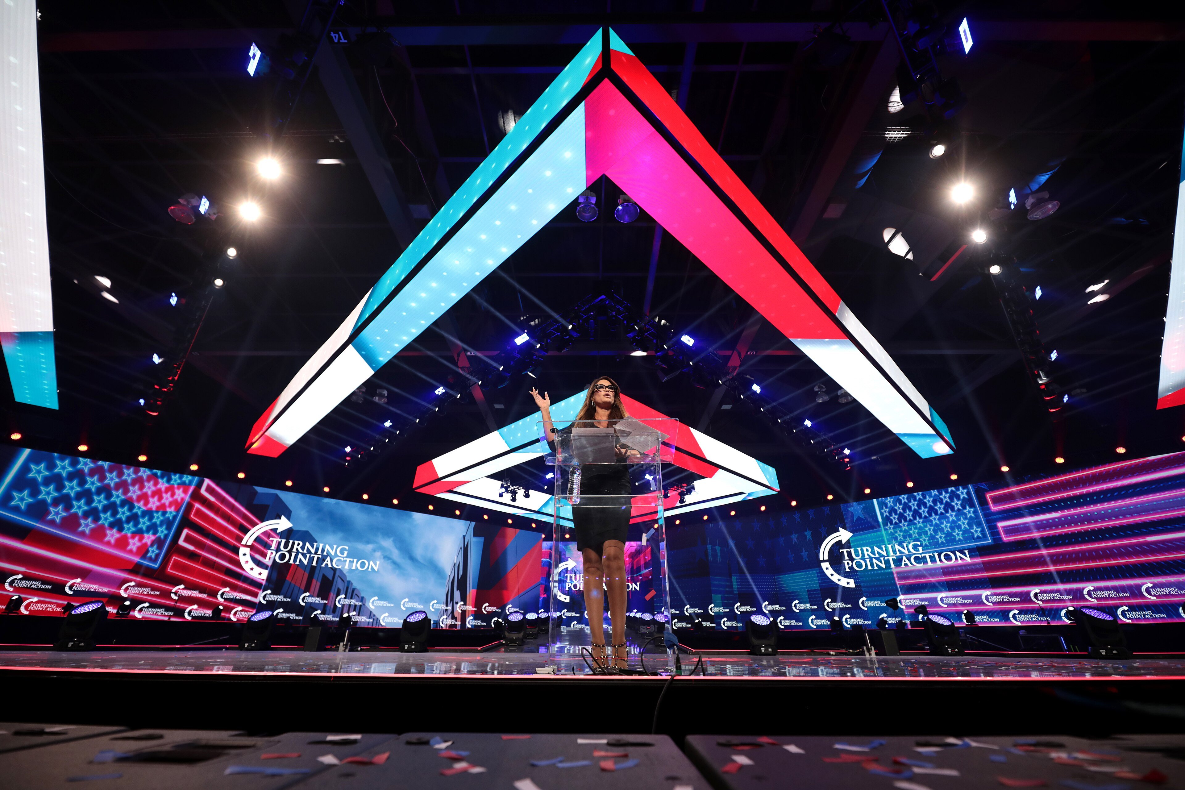 Kimberly Guilfoyle speaking into a microphone at AmericaFest in Phoenix, Arizona, in 2021