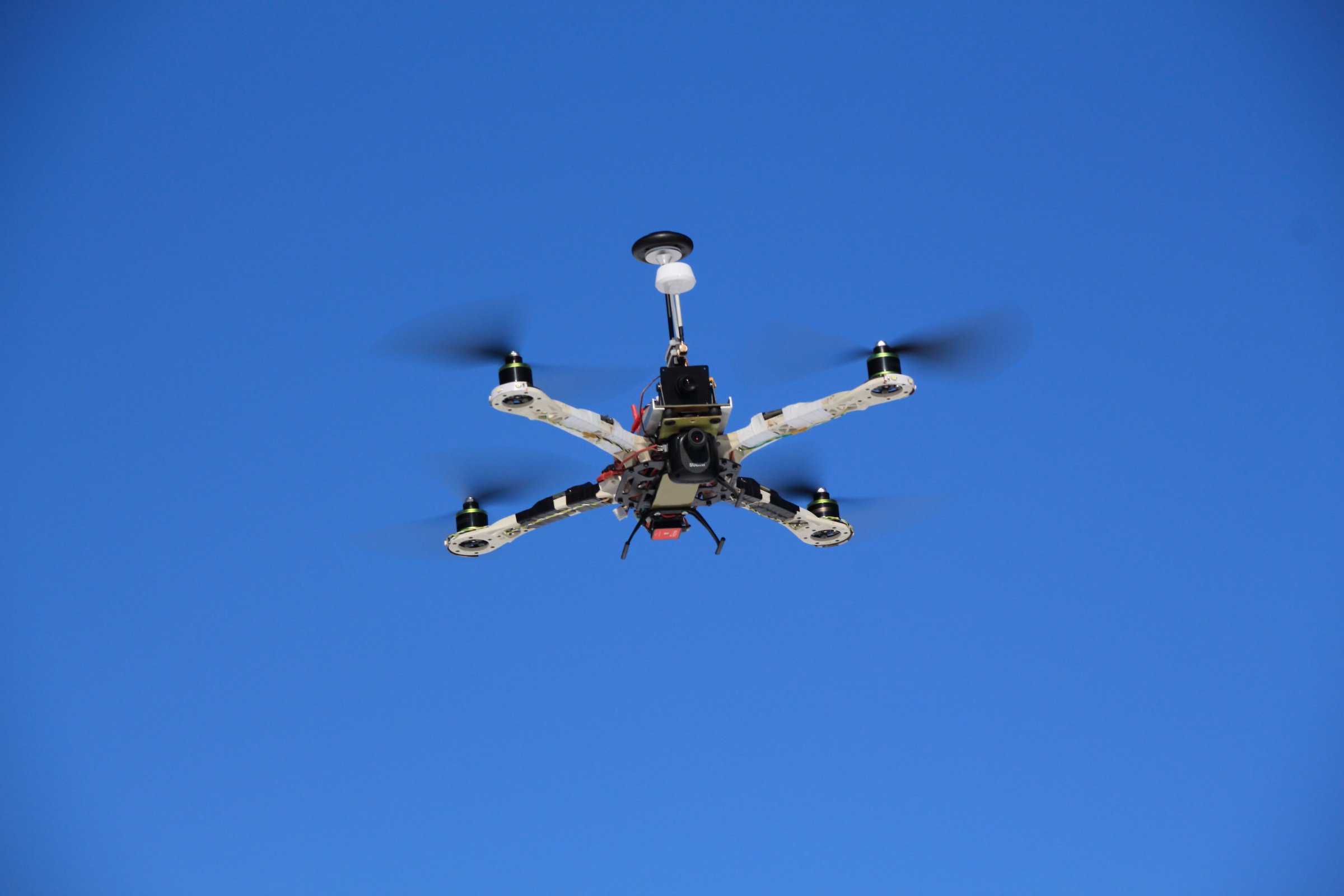 A multirotor drone in flight against a blue sky