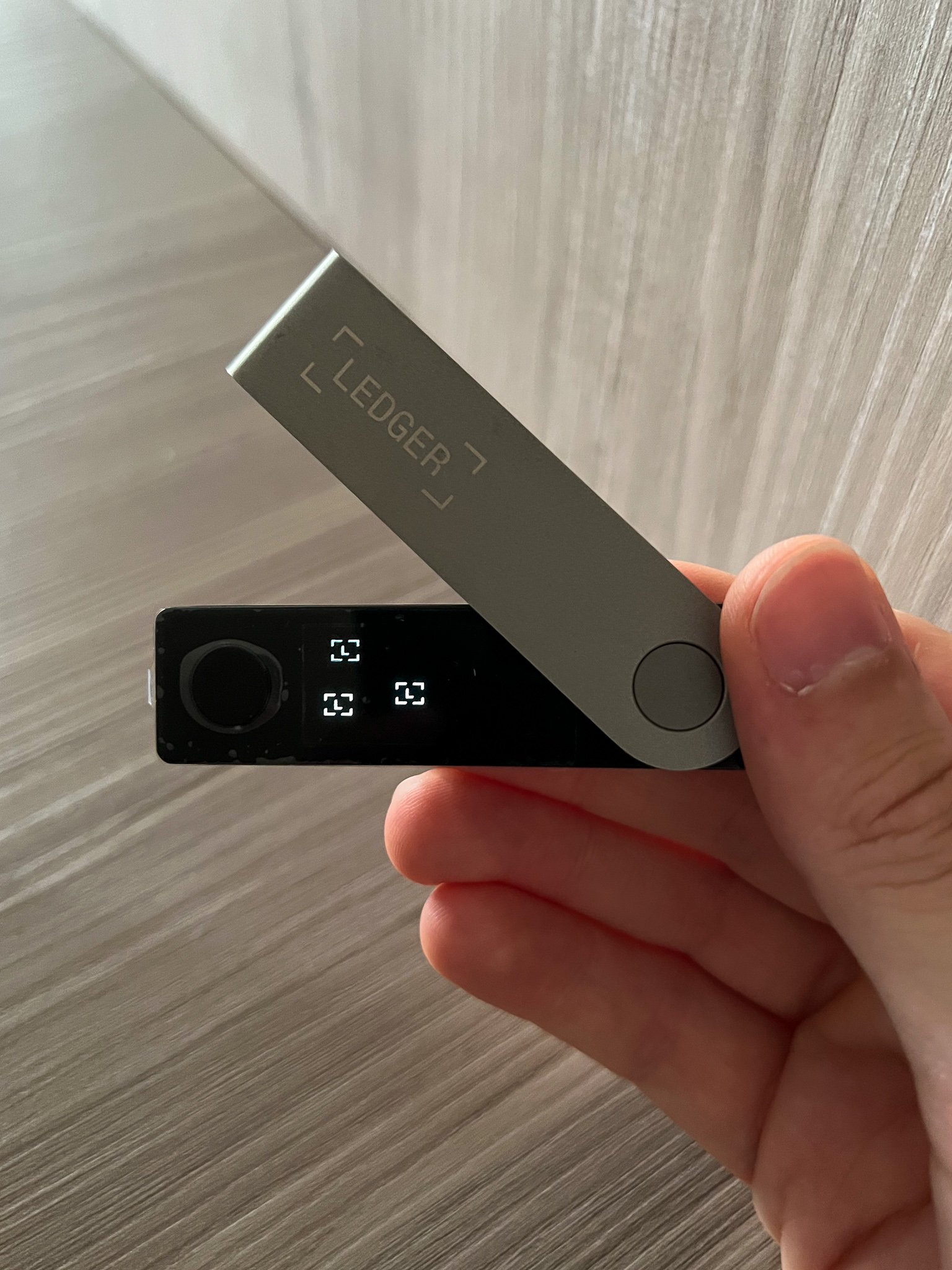 A hand holding a Ledger Nano X hardware wallet