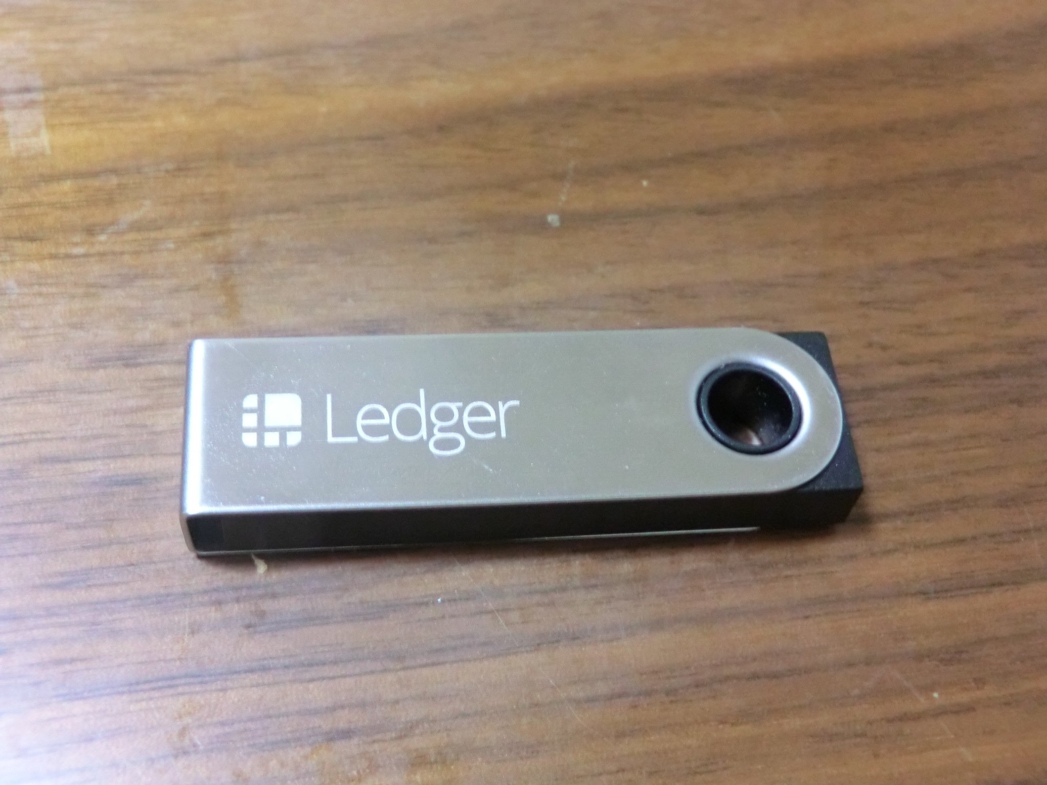 A Ledger Nano S next to its box, the seal and packaging are what buyers should inspect