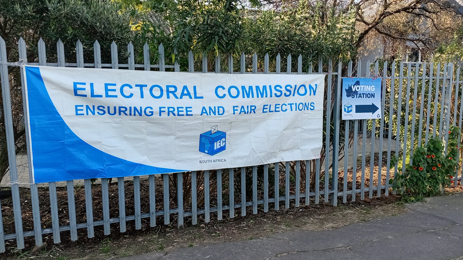 An Electoral Commission banner and a voting station sign on a school fence in Paarl