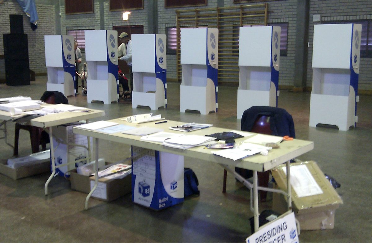 An IEC voting station with ballot booths set up inside a hall