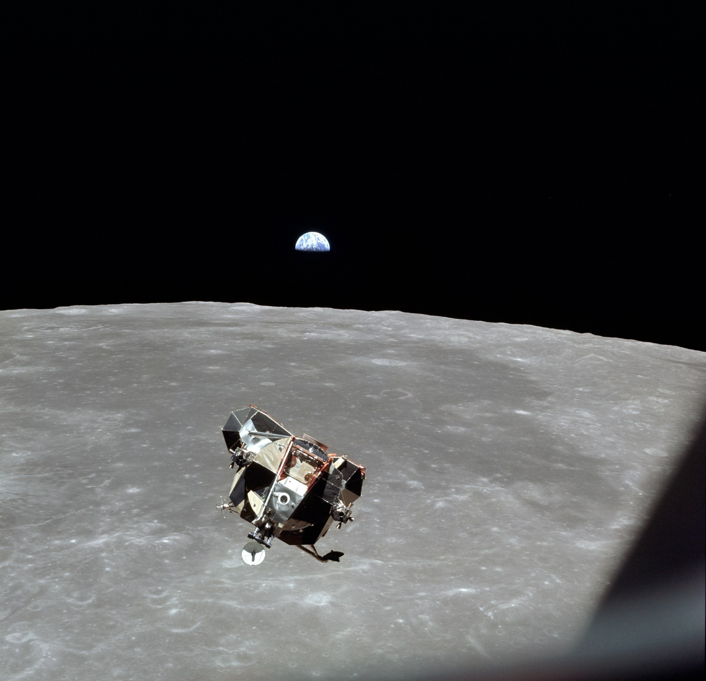 The Apollo 11 lunar module Eagle above the grey surface of the Moon, with a small blue Earth in the black sky