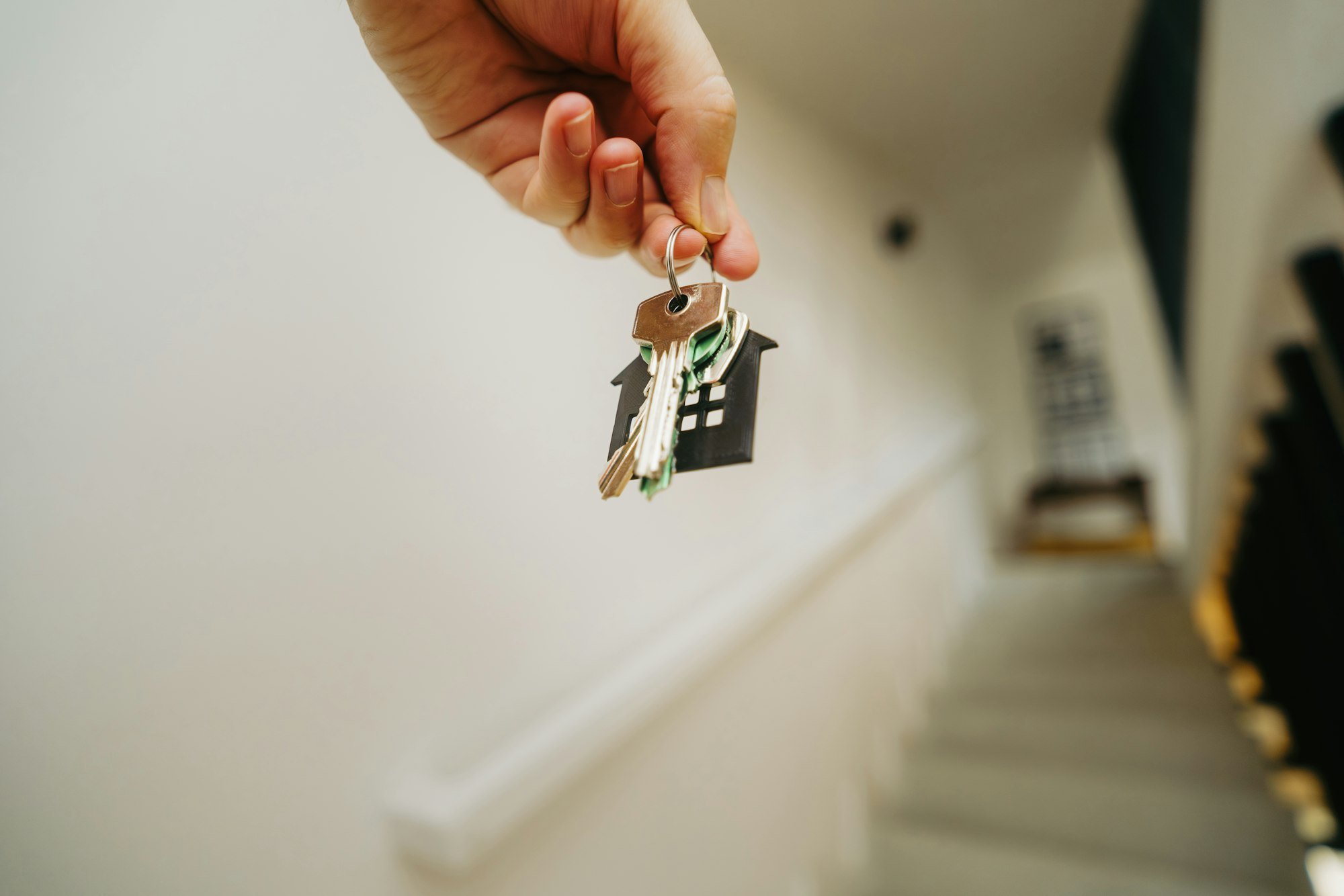 A hand holding a single house key, the moment a home loan closes