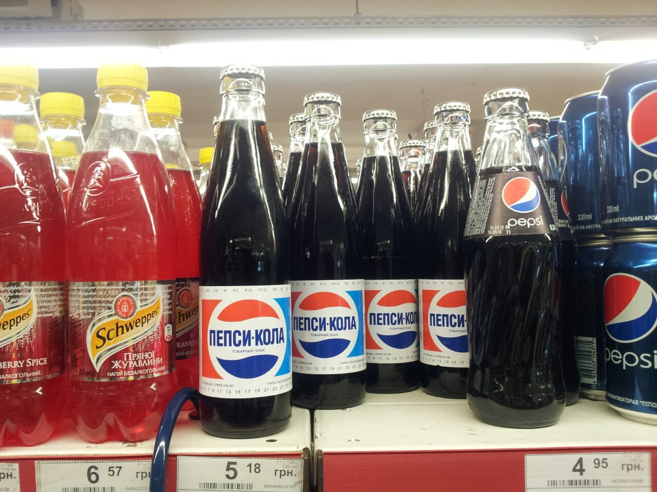Pepsi bottles lined up on a supermarket shelf