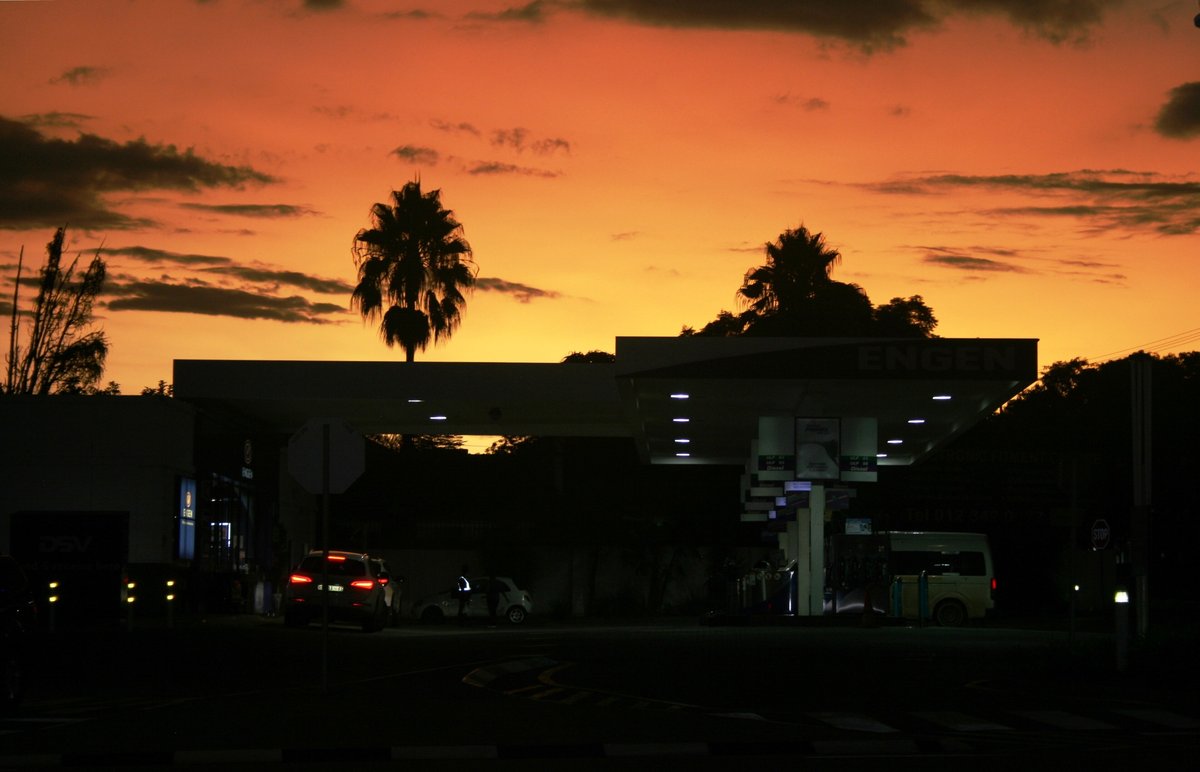 An Engen station in Hatfield, Pretoria, lit up at dusk under palm trees