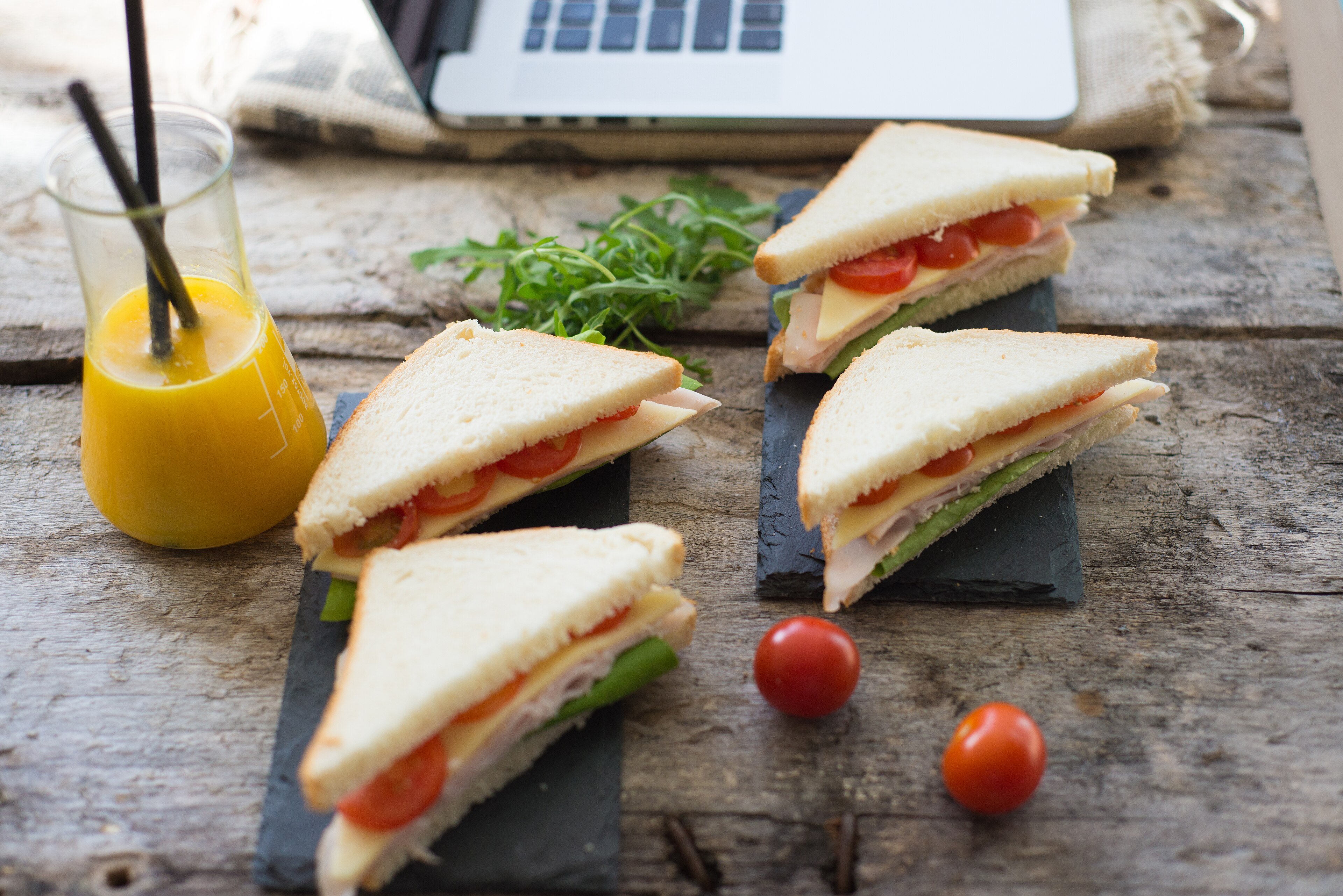 A platter of sandwiches with a glass of juice on a wooden table