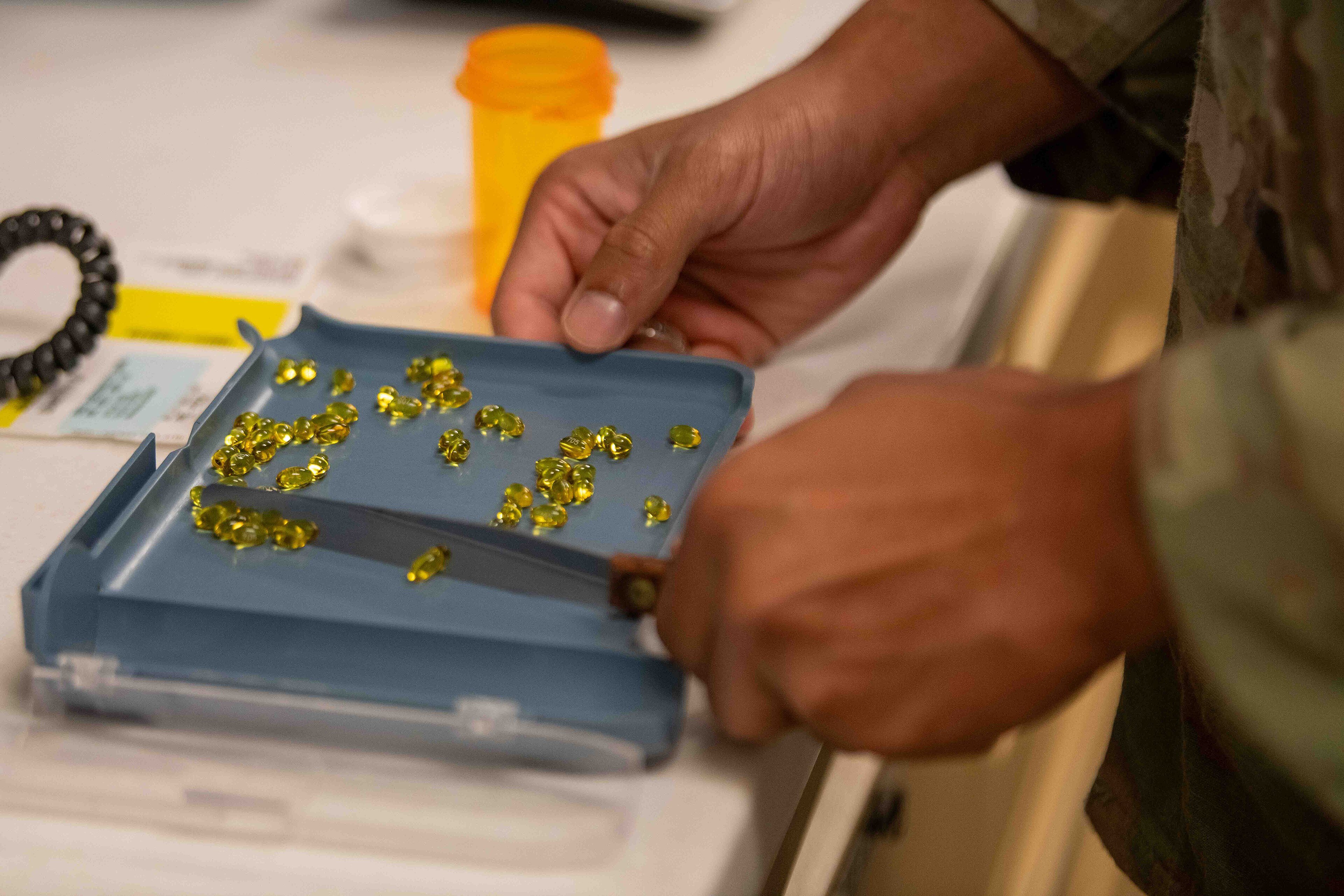 A pharmacy technician counting prescription pills on a tray