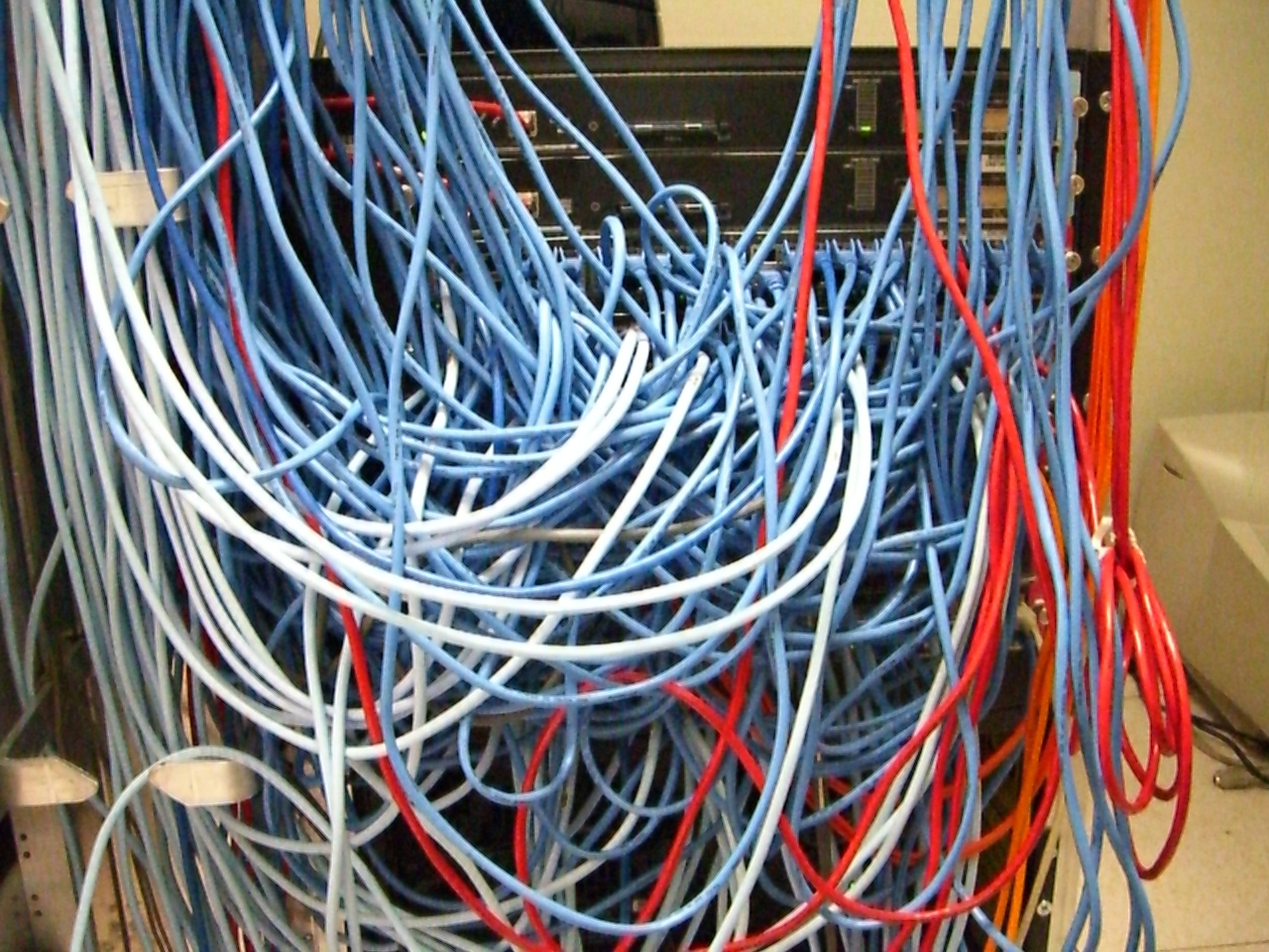 A tangle of network cables behind a server rack, the kind of machine that had to be patched or switched off