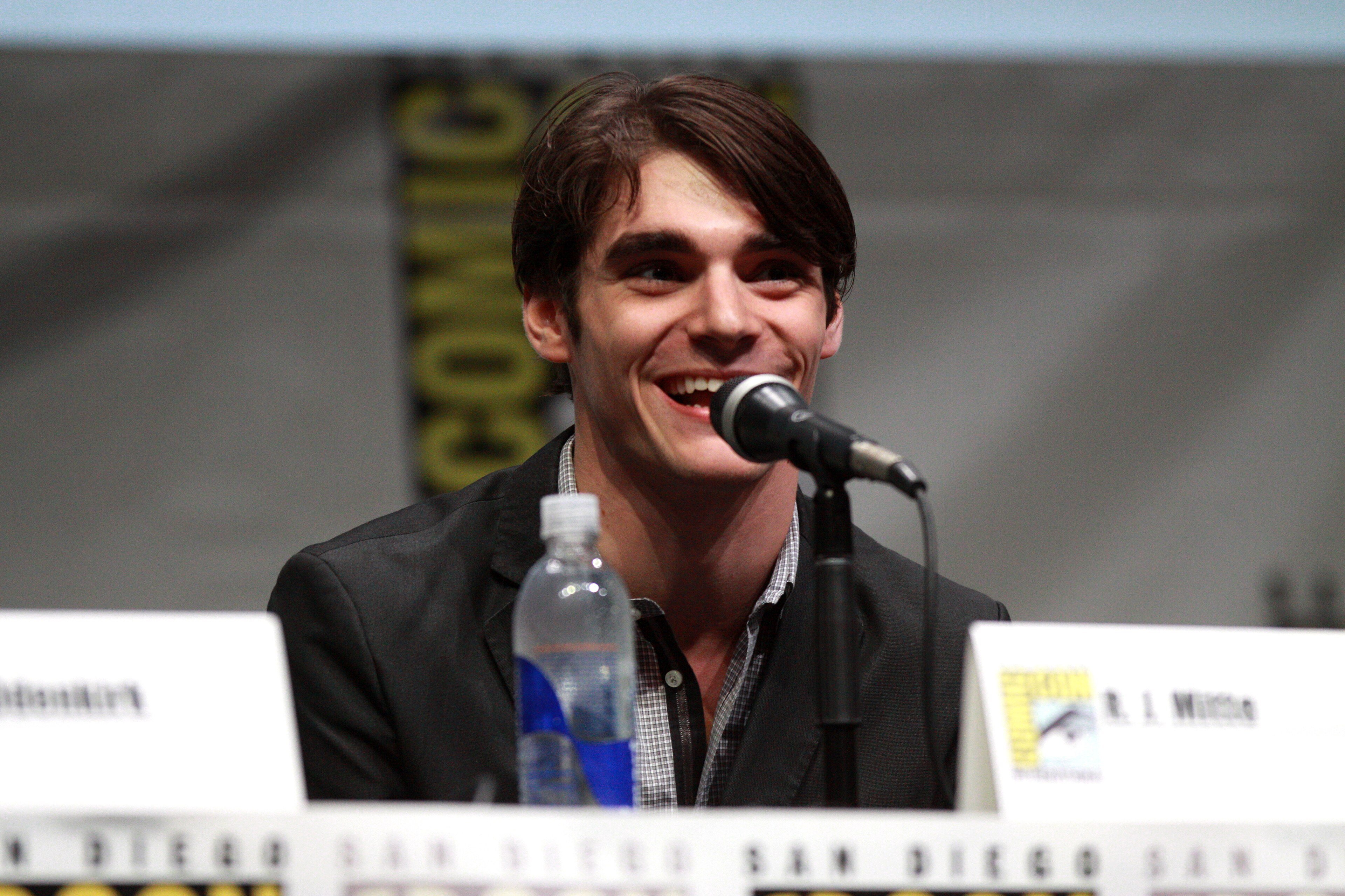 RJ Mitte smiling at a microphone on a comic convention stage