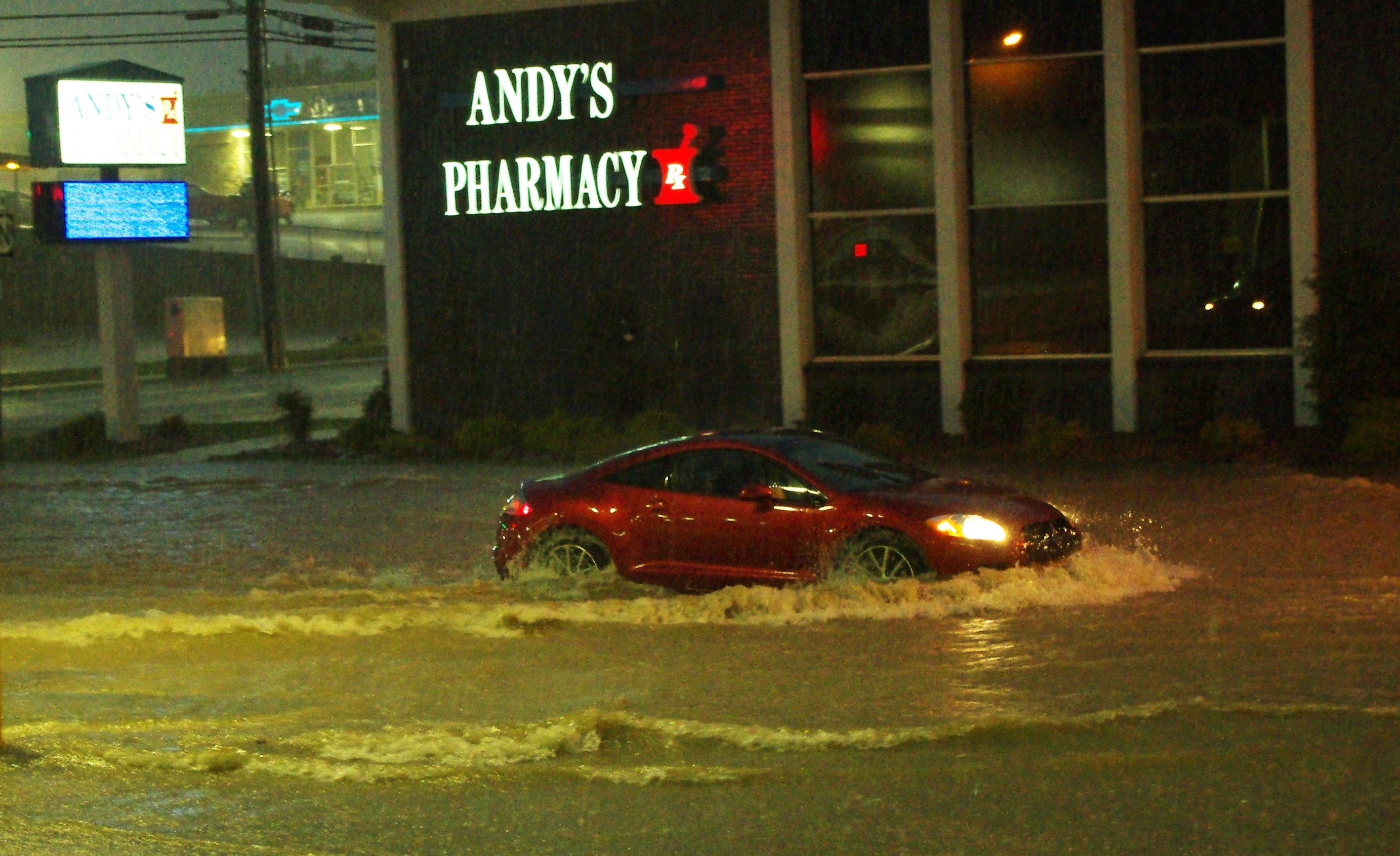 A car pushes through flash flood water on a city street