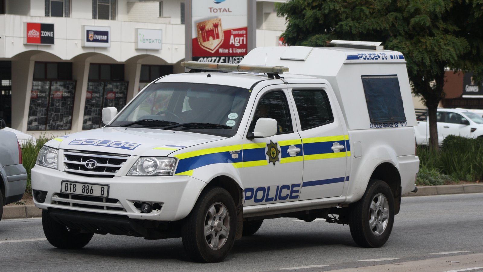 A white South African Police Service patrol van with blue and yellow markings on a street