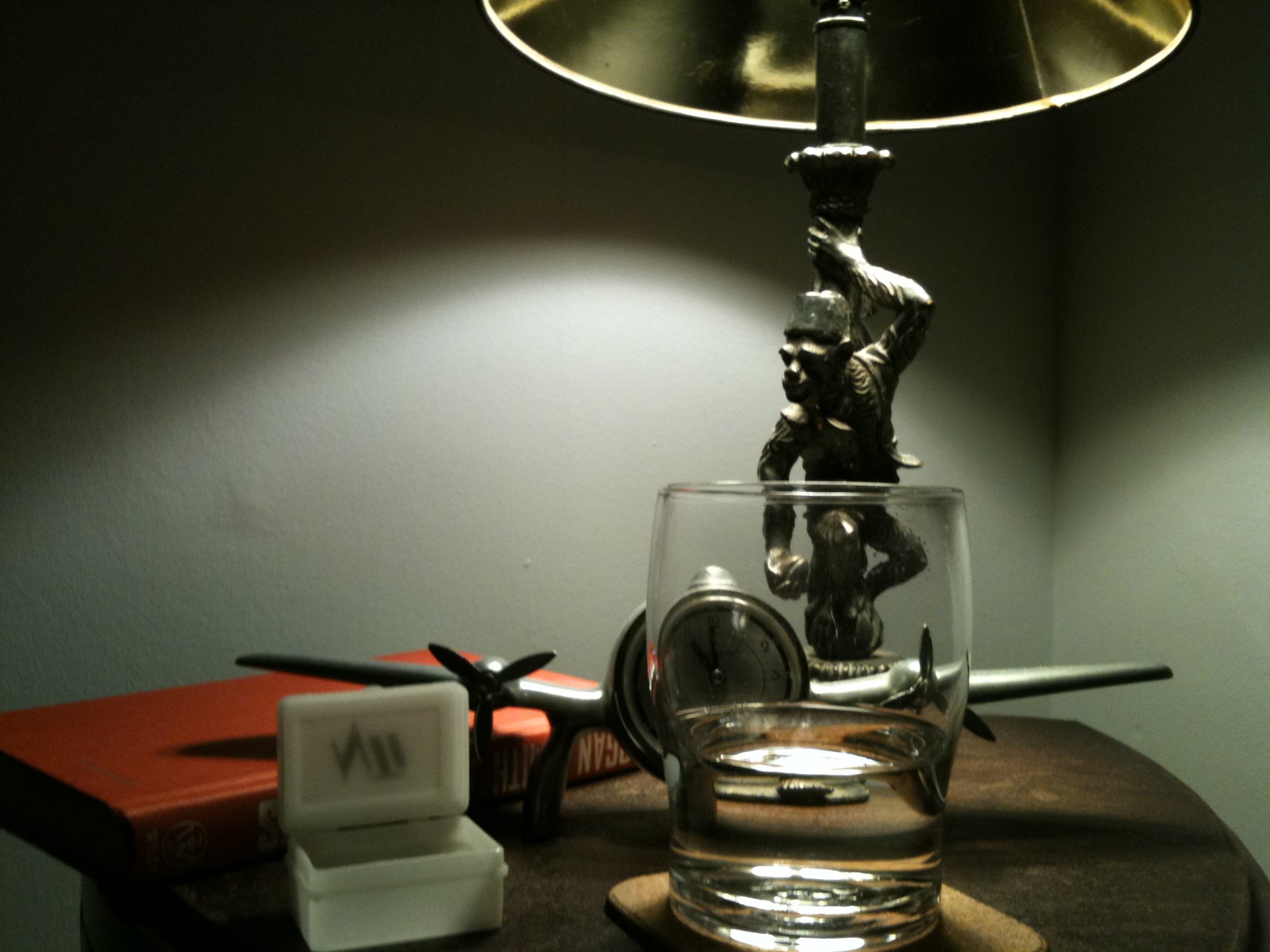 A bedside table with a lamp and alarm clock next to a bed