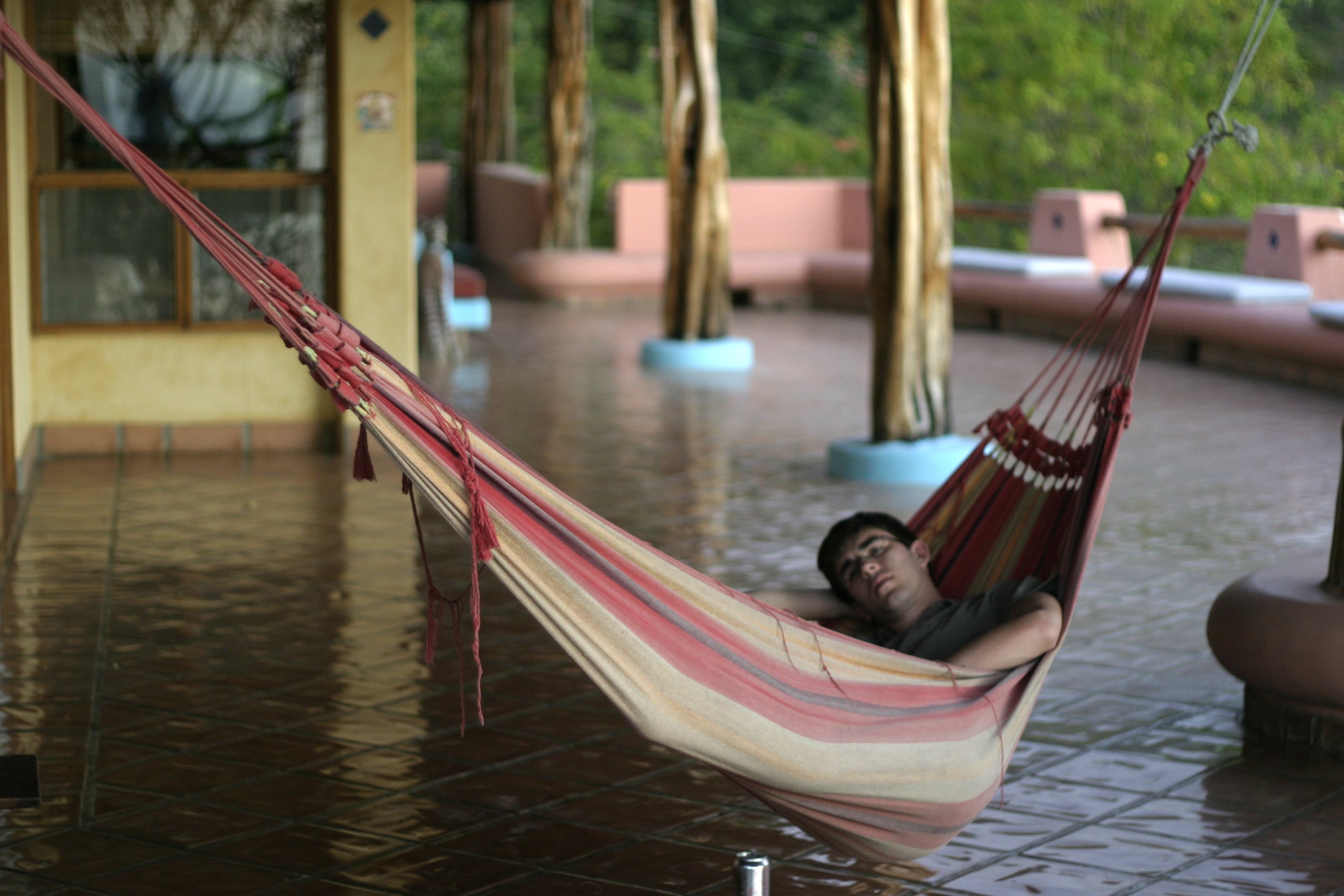 A man napping in a hammock on a covered patio