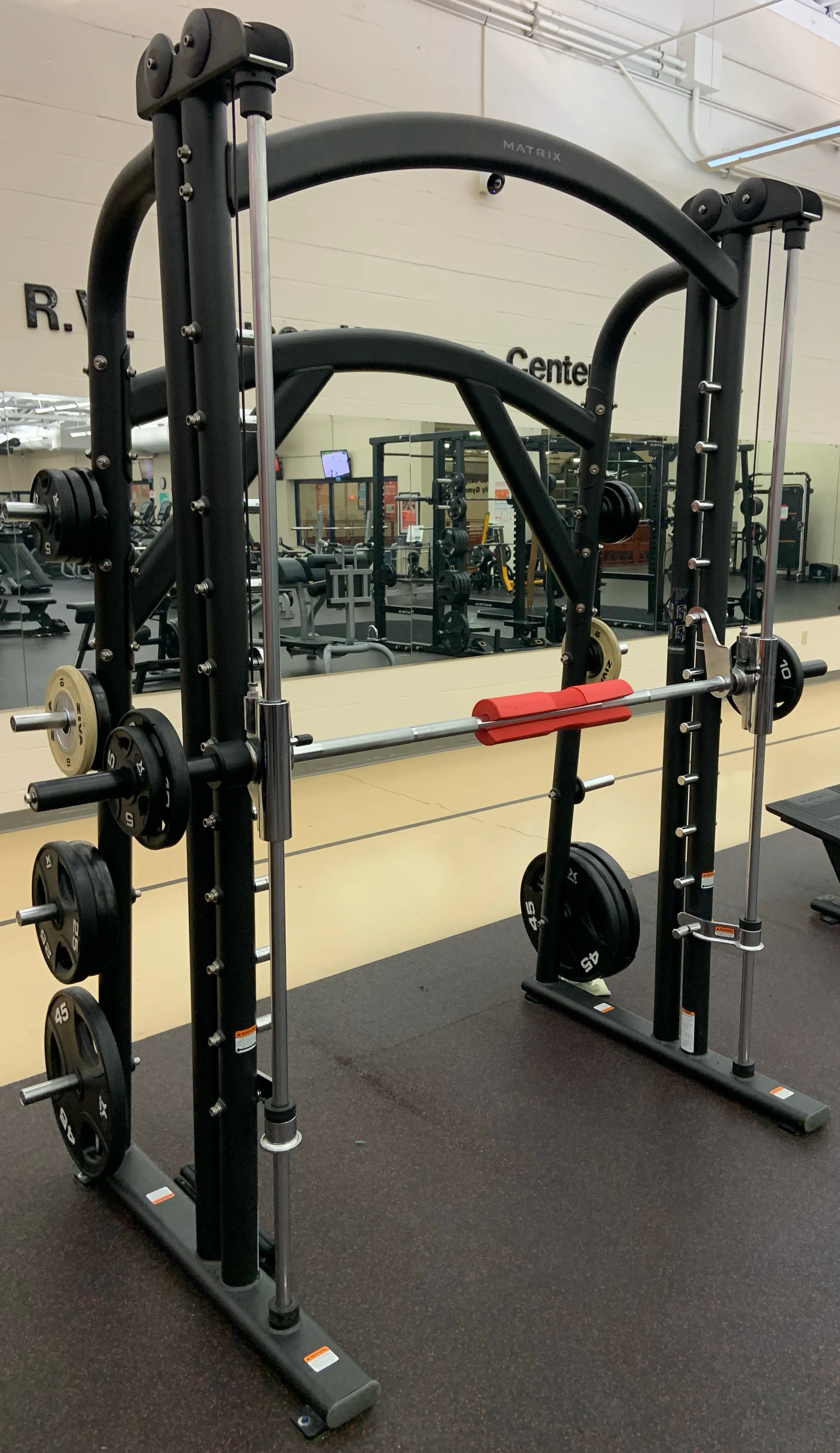 An empty Smith machine in a gym, with the bar locked onto its fixed steel rails