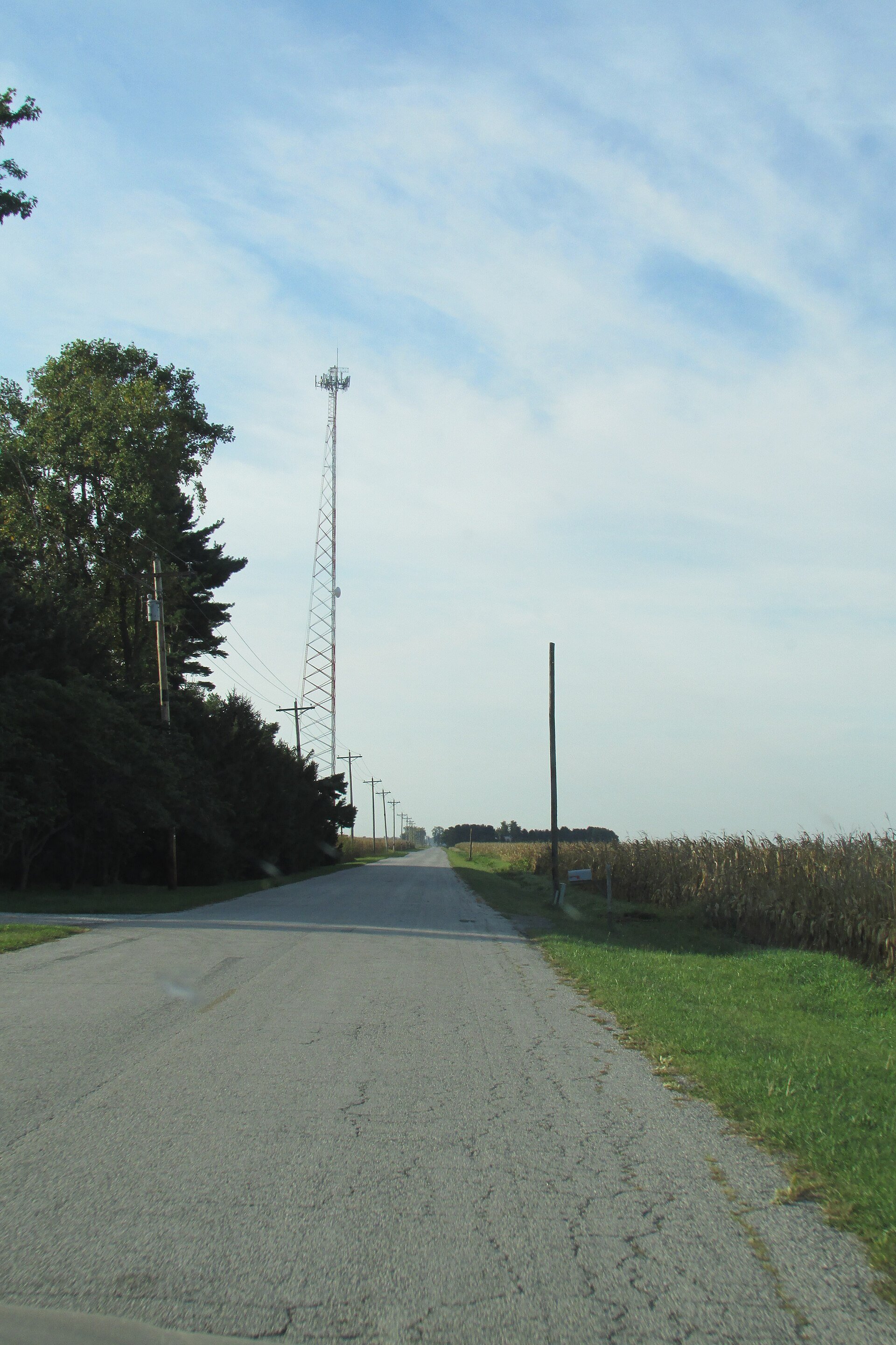 A tall steel cell tower standing in flat farmland near Wanatah, Indiana