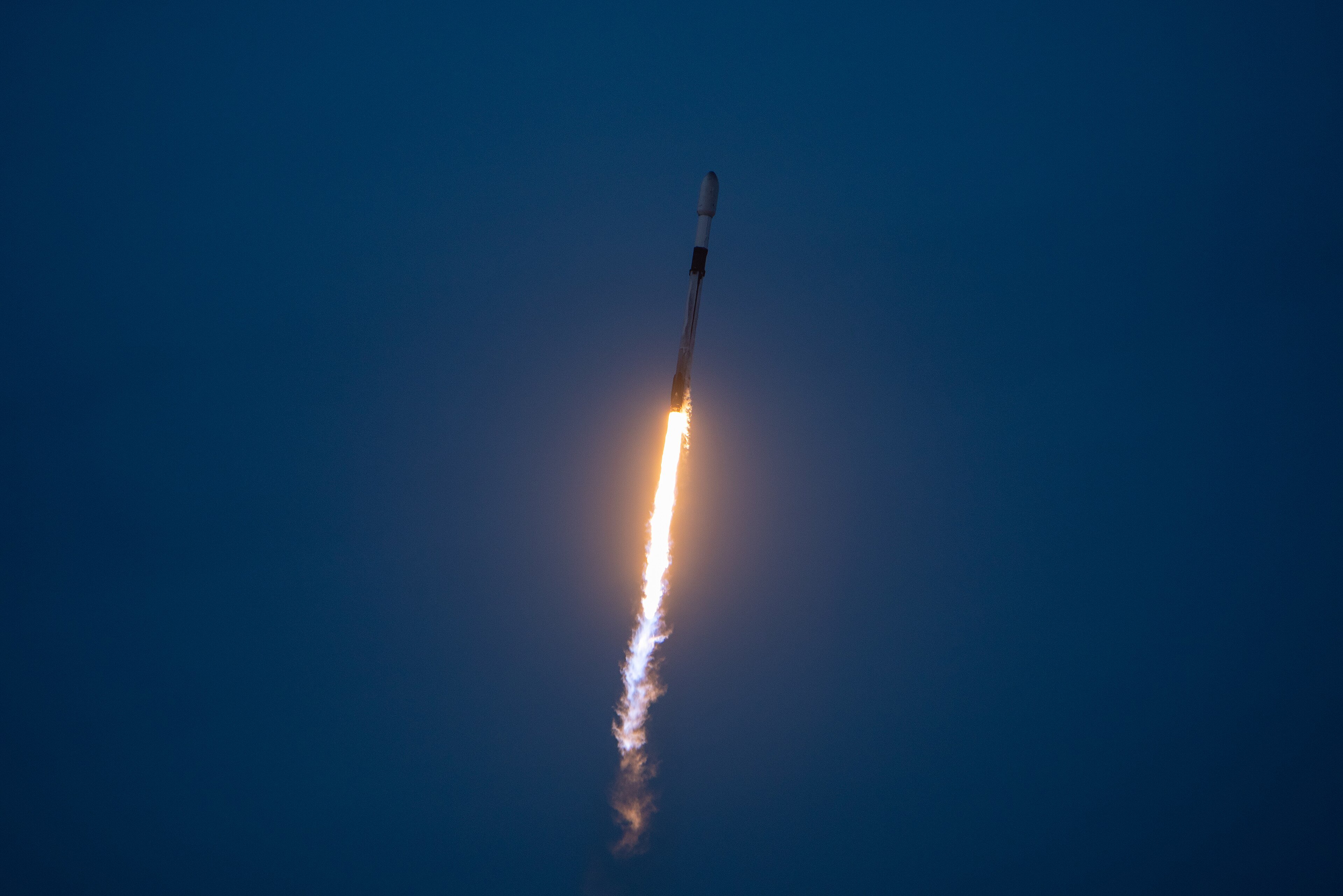 A Falcon 9 rocket lifting off from Cape Canaveral on a column of flame, carrying 23 Starlink satellites