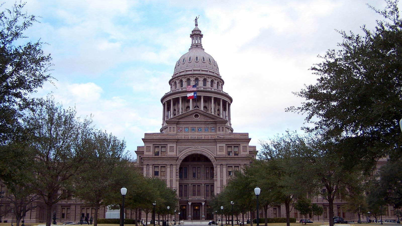 The pink granite dome of the Texas State Capitol in Austin with the US and Texas flags flying