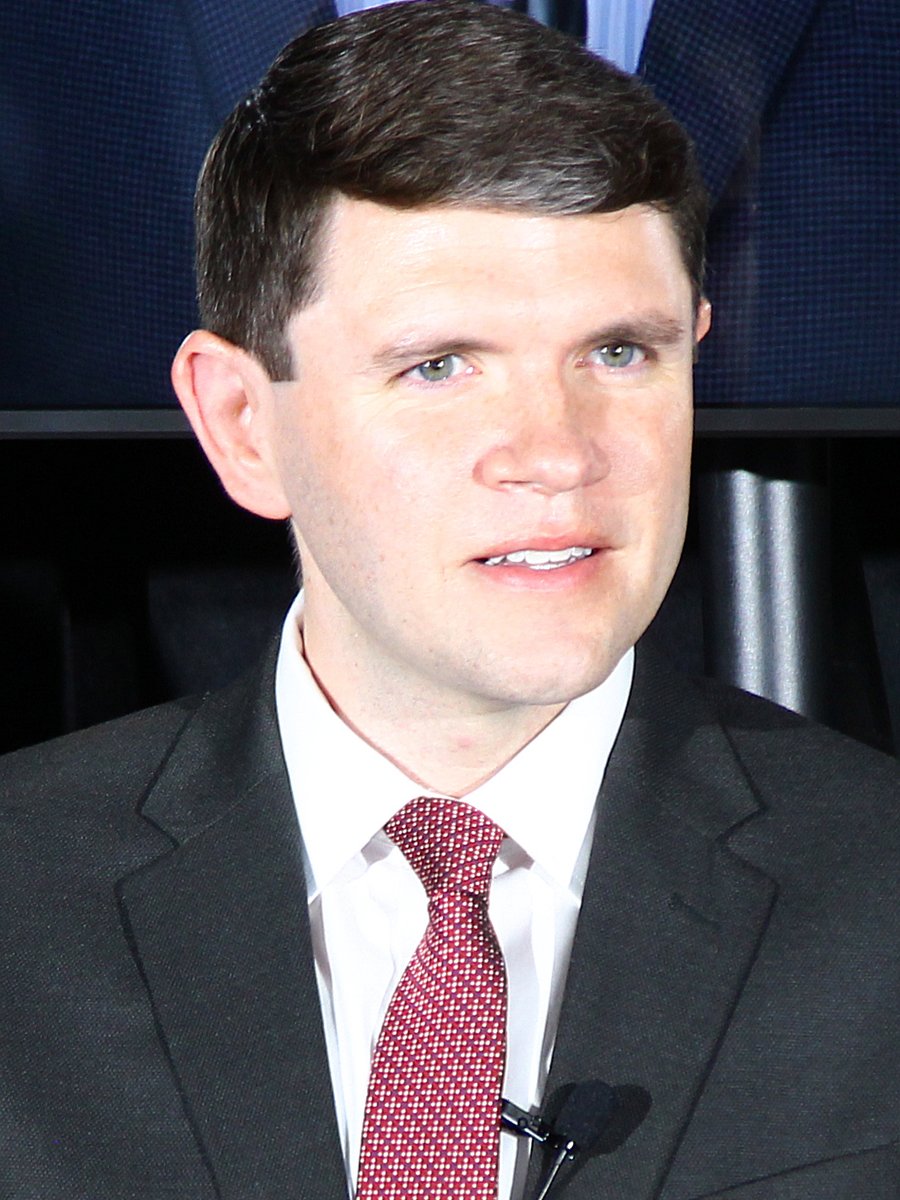 Texas state representative James Talarico in a dark suit and red tie, speaking at an event in Austin