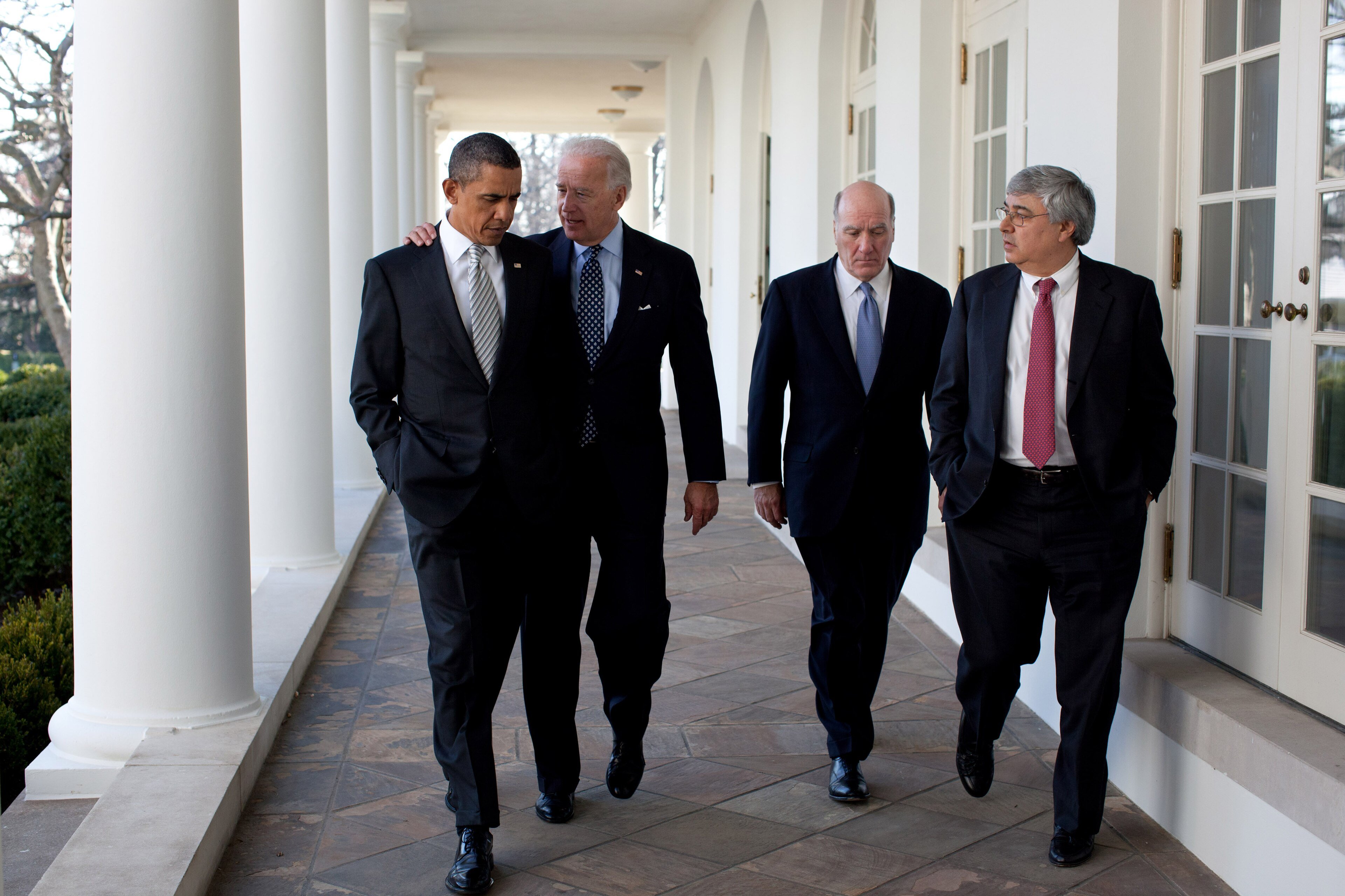 Barack Obama and Joe Biden walk side by side along the White House Colonnade with two aides
