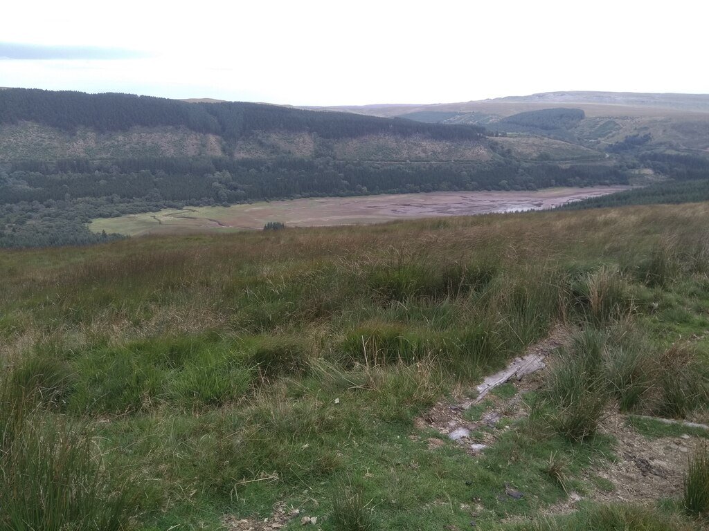 A UK reservoir drained during an earlier drought, its lake bed exposed on a dry hillside