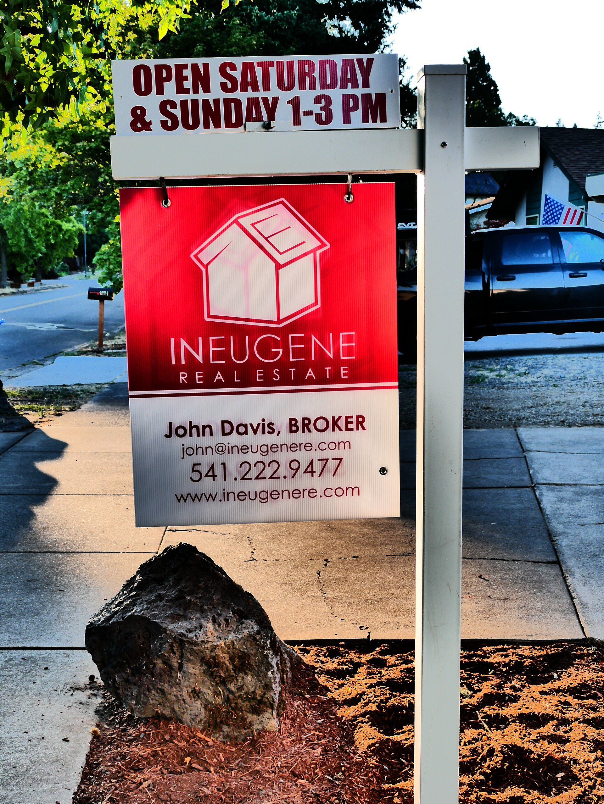A home for sale sign with an open house sign in a US neighborhood