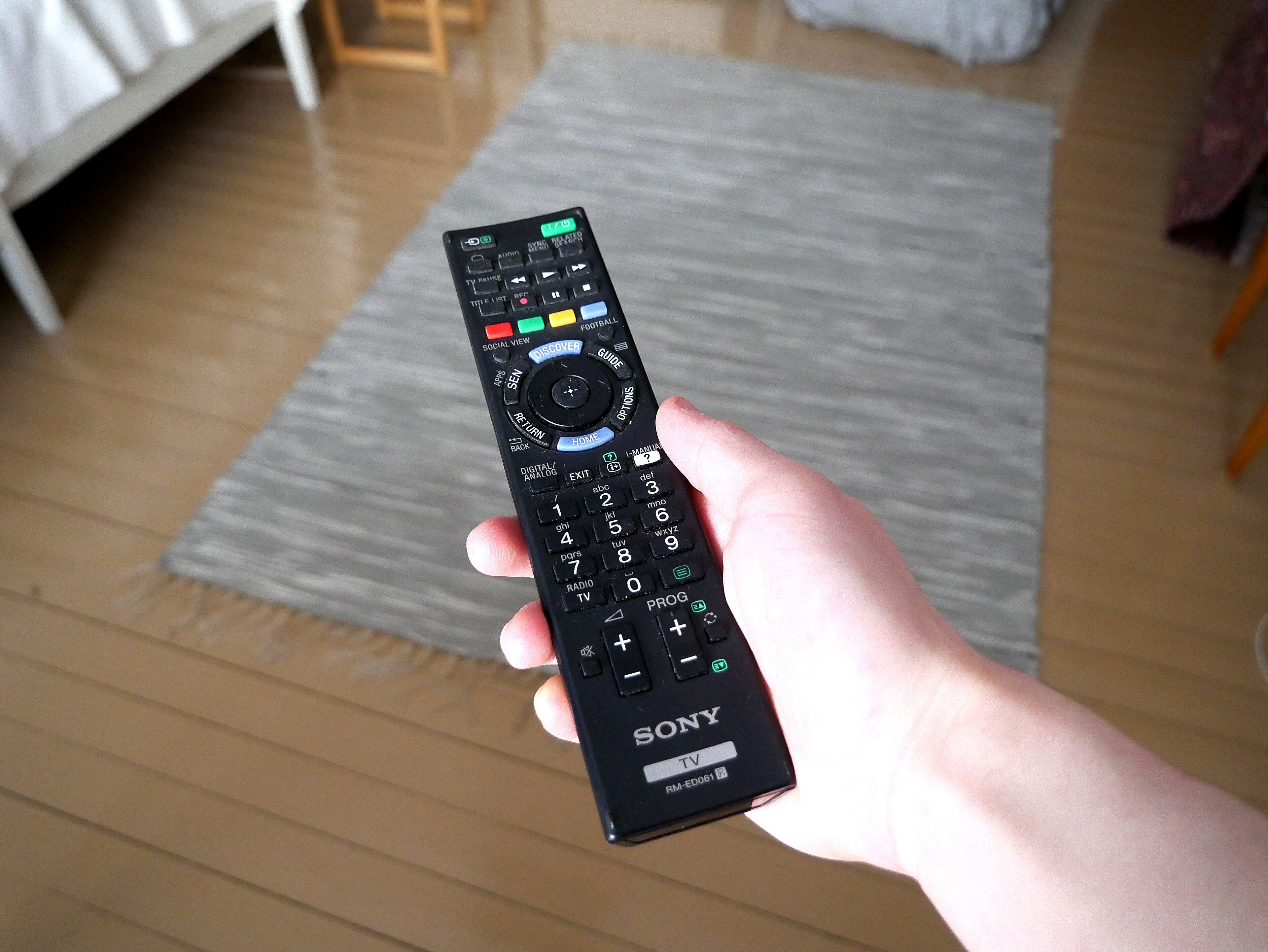 A TV remote in hand, held up toward the screen